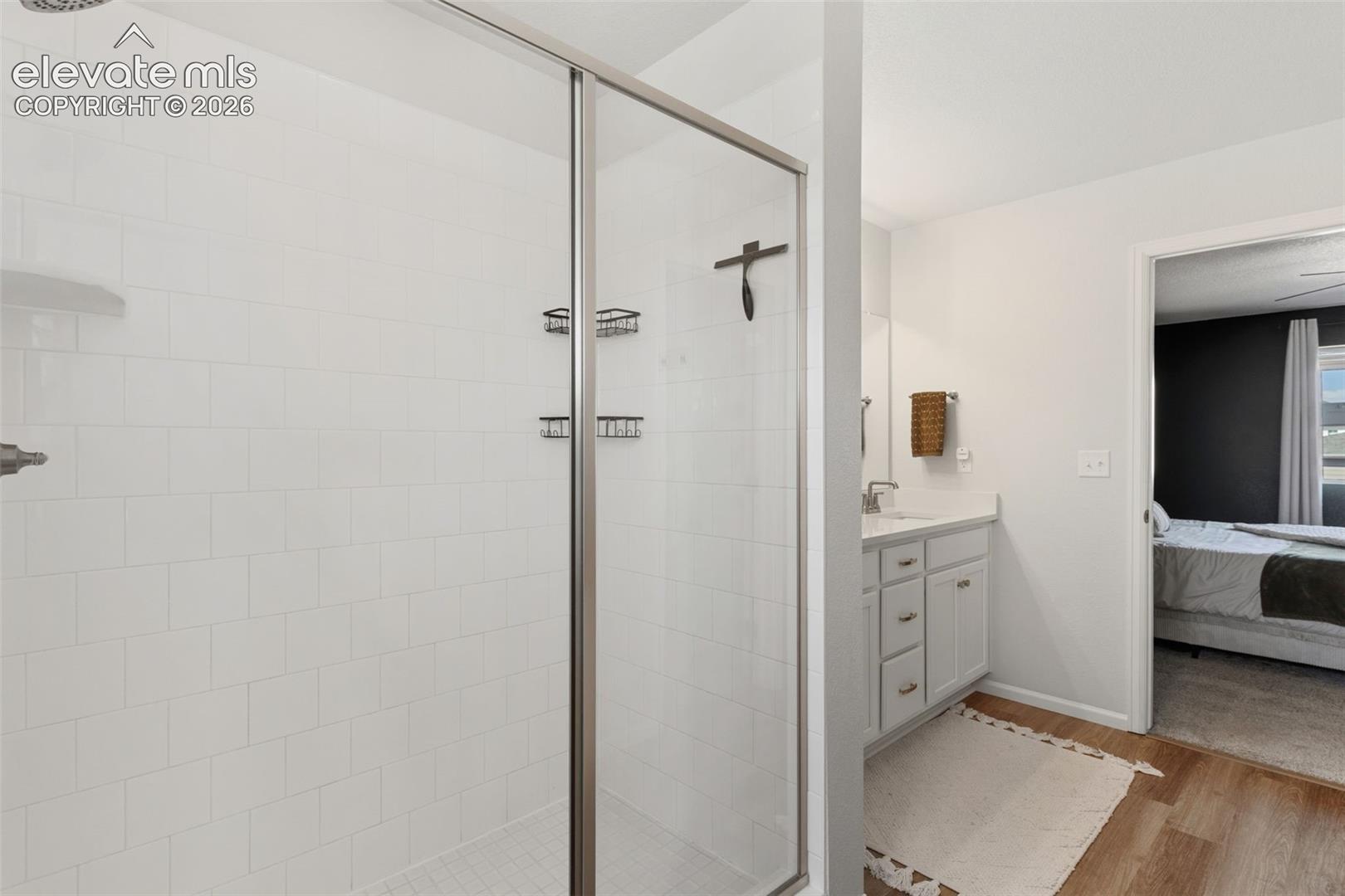 Walk-in shower featuring a frameless glass enclosure, white subway tile surround, built-in shelving, and a rain showerhead