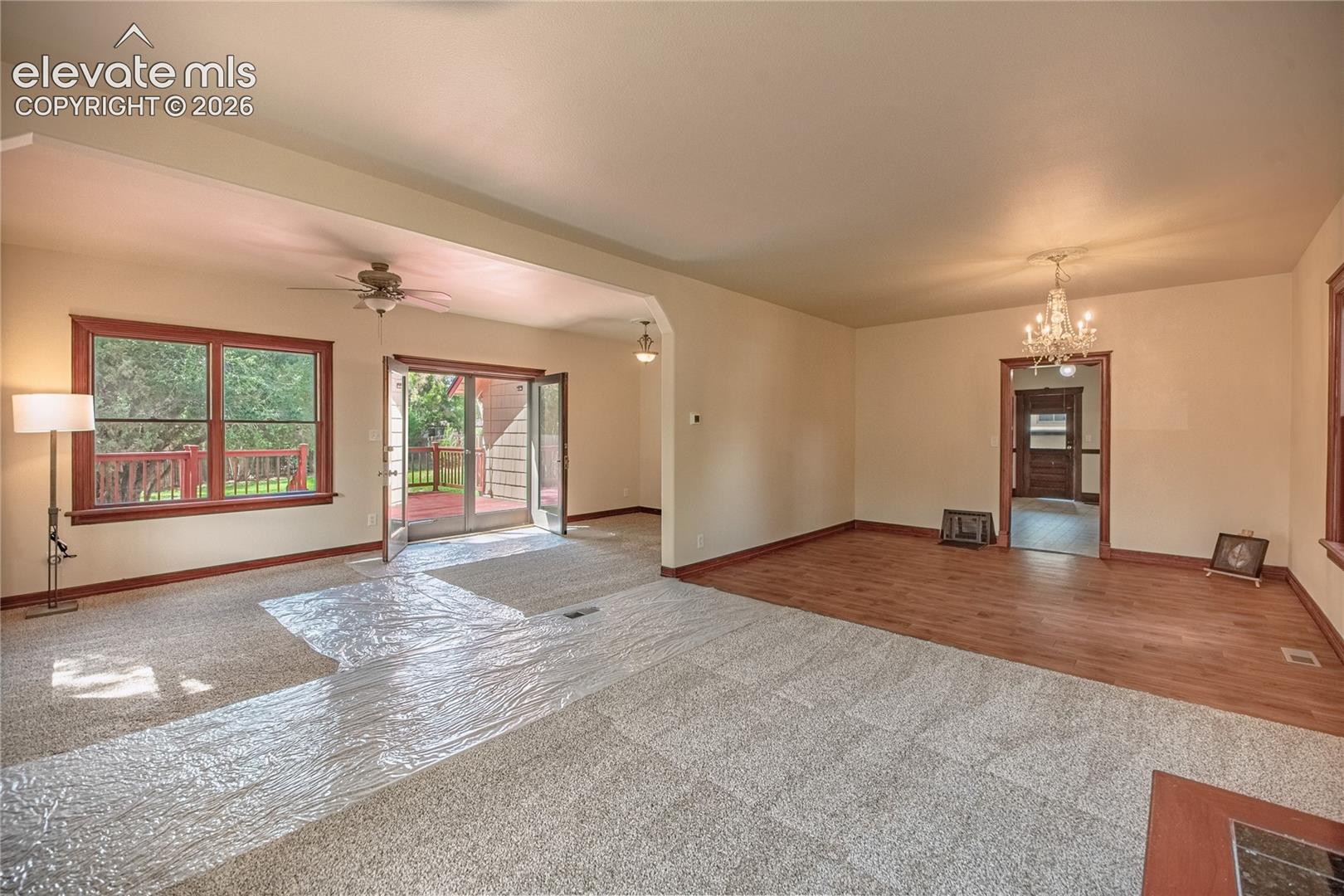 Expansive interior featuring carpeted and wood-finish flooring, a ceiling fan, and a chandelier