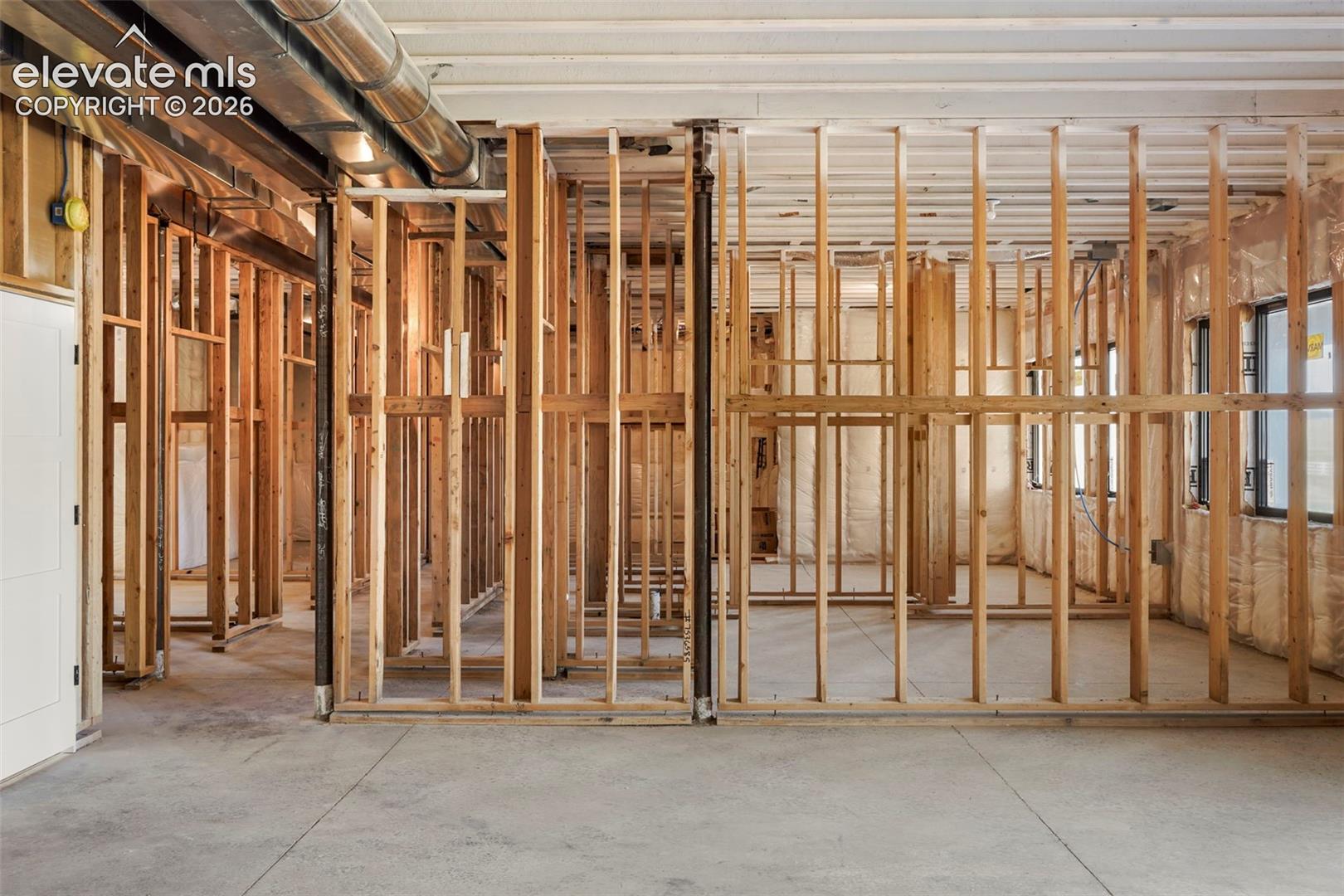Exposed wood framing with concrete flooring, visible ductwork, and multiple windows