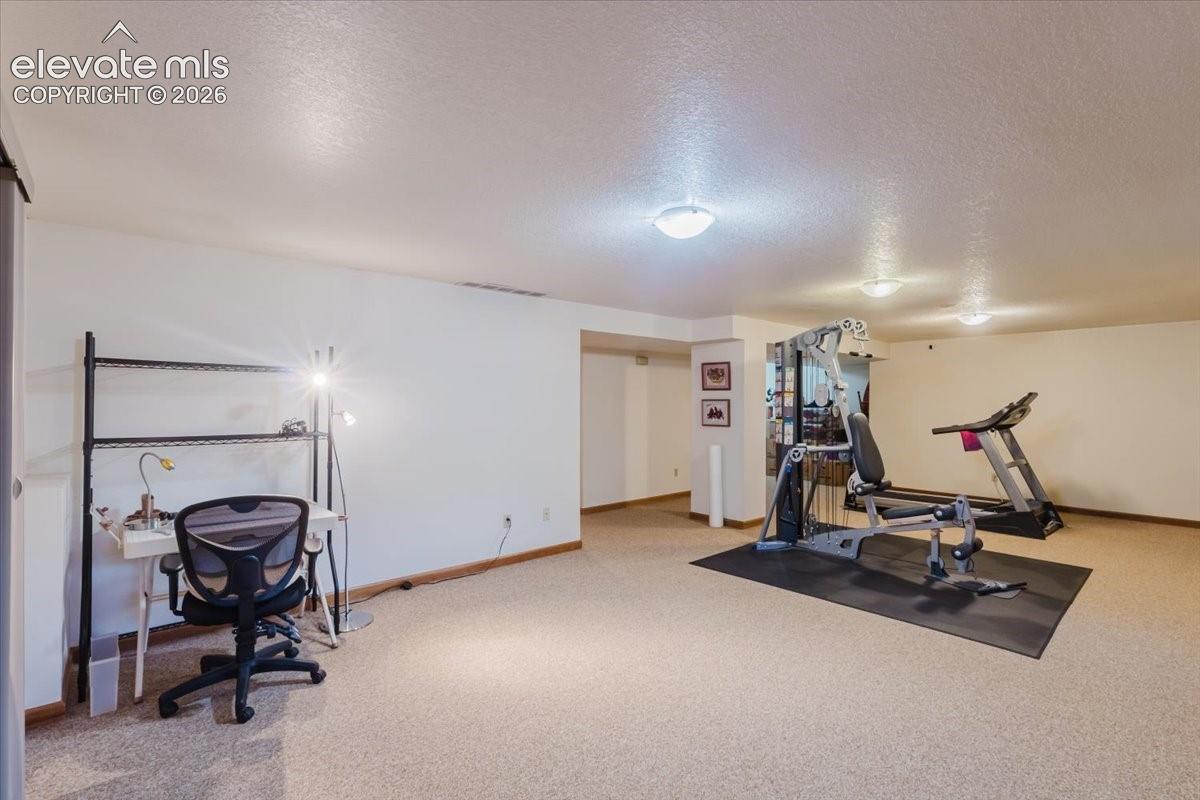Spacious room with light-colored carpeting, white walls, and built-in ceiling light fixtures