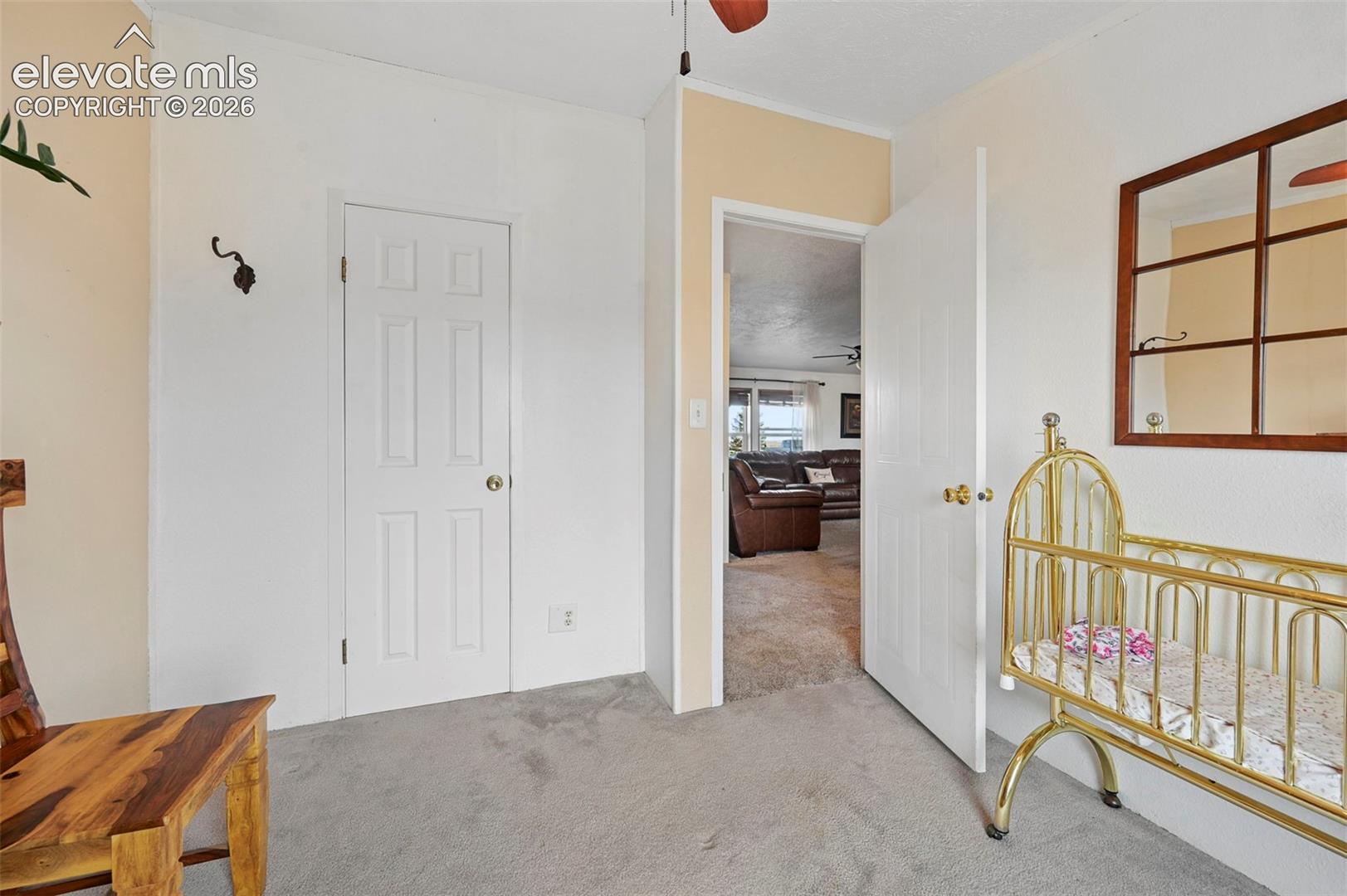 Bedroom #2 Interior room featuring neutral wall paint, carpeted flooring, two white interior doors, and a decorative wood-framed wall mirror