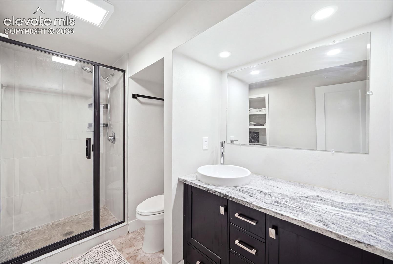 This basement-level bathroom has an oversized shower and graite countertops. 