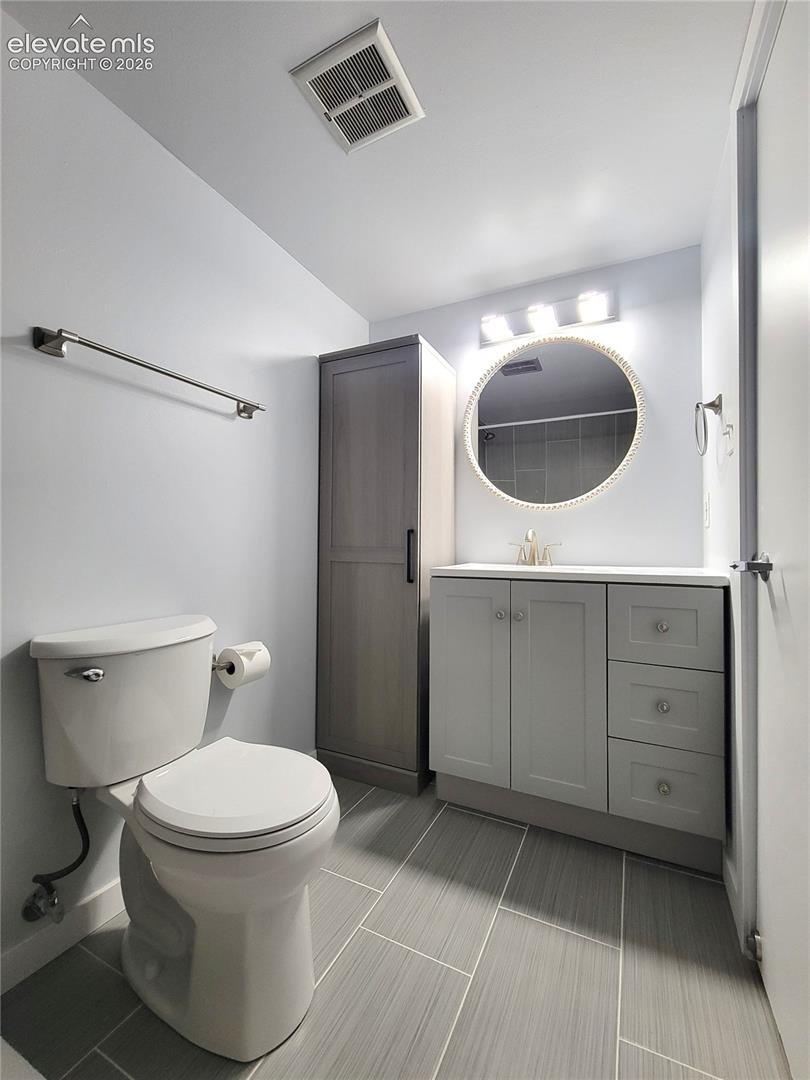 Primary Bathroom featuring light gray wall paint, a white toilet, and gray tile flooring
