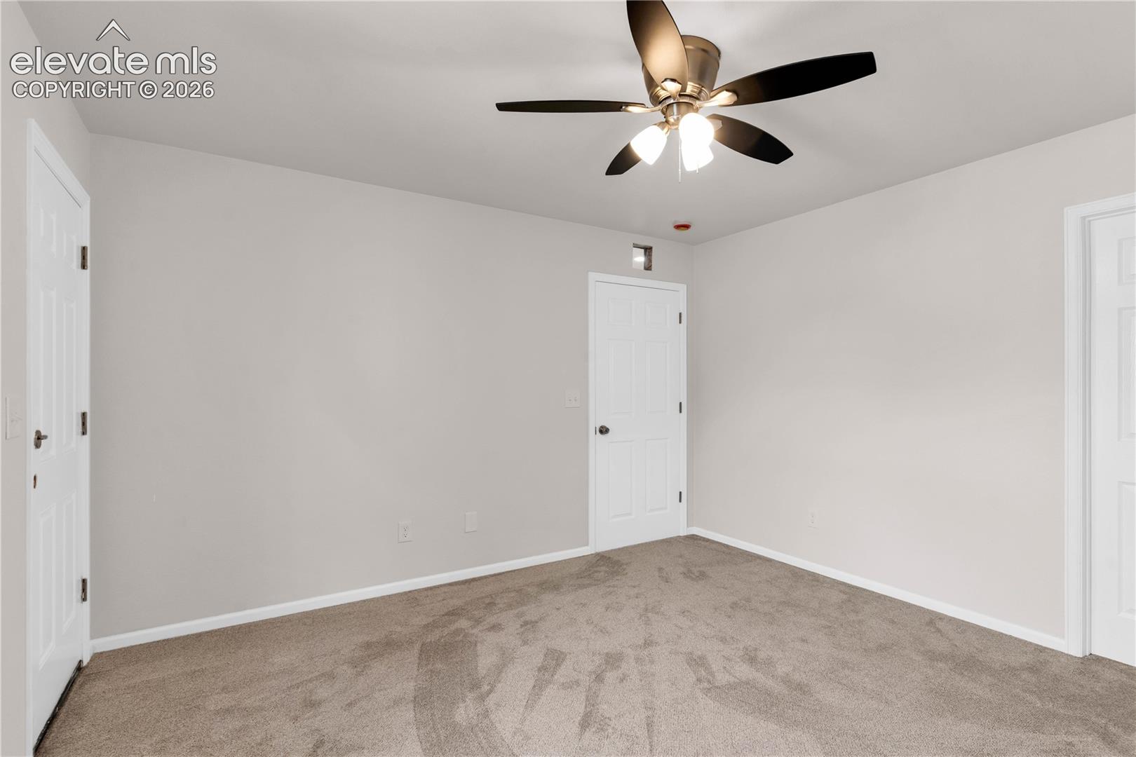Neutral wall finish featuring wall-to-wall carpeting, multi-panel doors, and a ceiling-mounted fan with integrated lighting