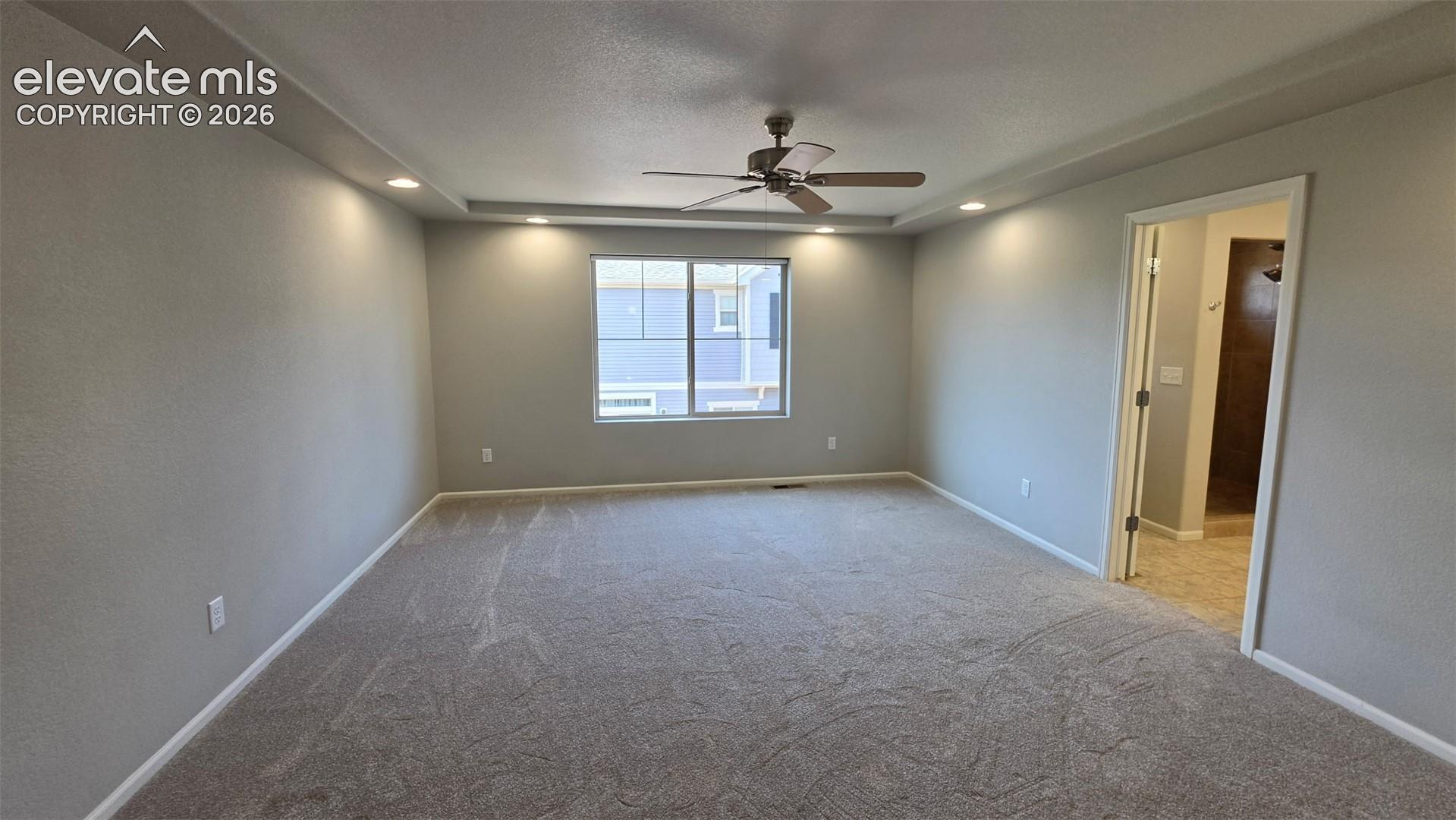 Room featuring a tray ceiling, recessed lighting, neutral carpeting, and a ceiling fan