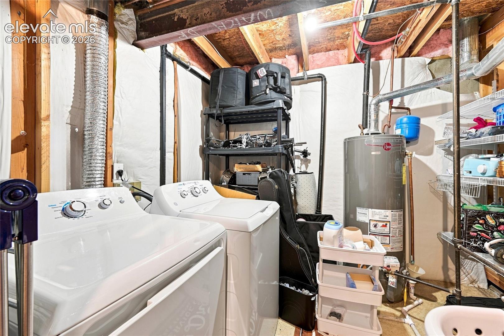 Utility area featuring a water heater, exposed piping, metal shelving, and laundry hookups