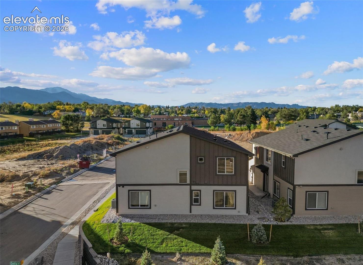 Multi-story structure featuring a stucco and vertical board-and-batten exterior, asphalt shingle roofing, and mountain range backdrop
