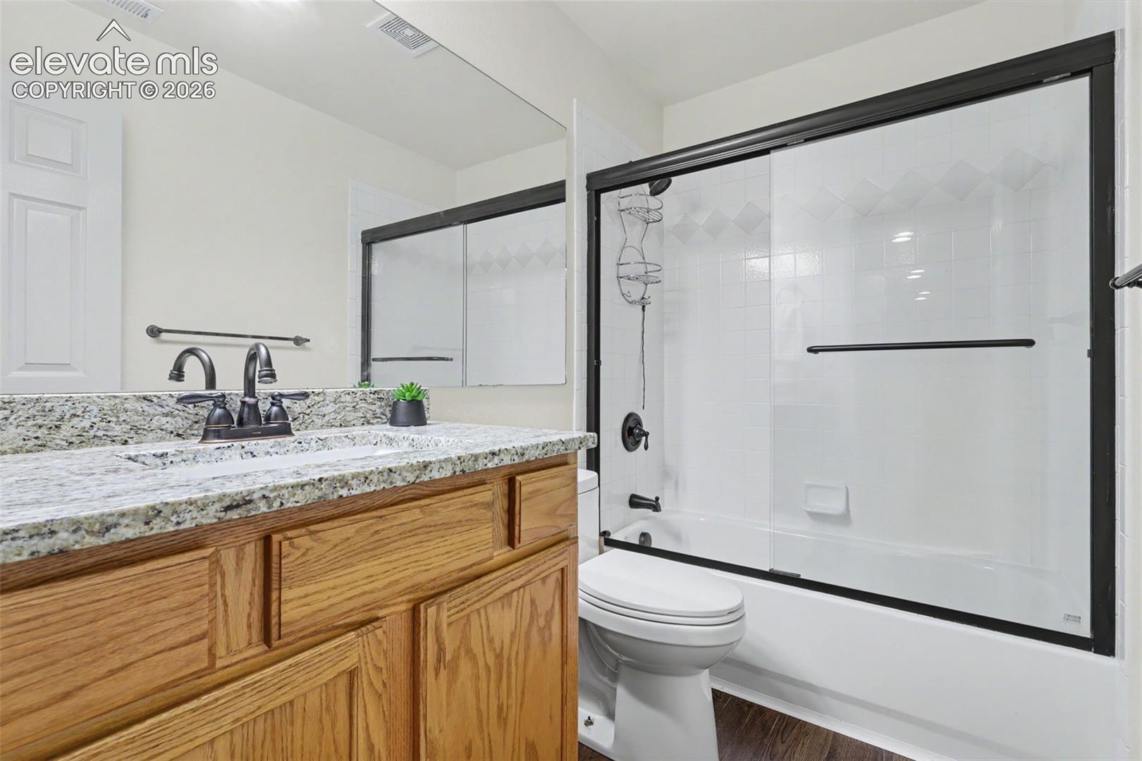 Bathroom featuring a wood-finish vanity with a stone countertop and an undermount sink