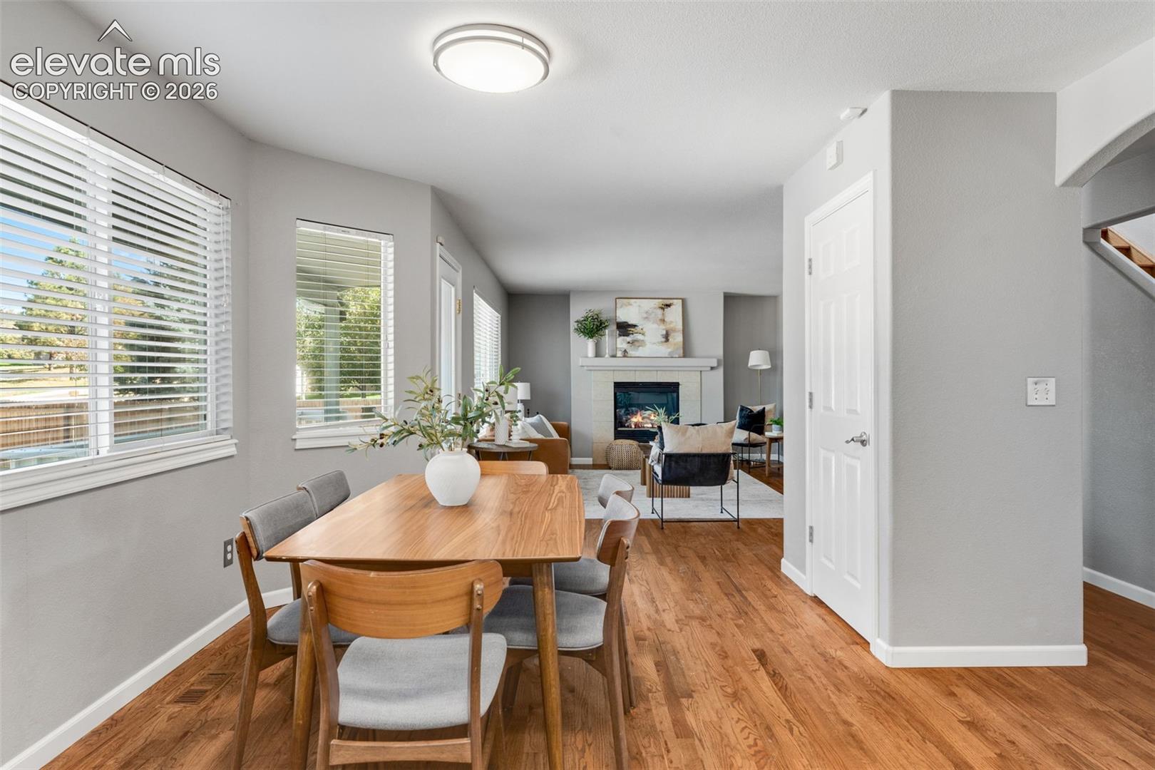 Interior featuring wood-finish flooring, a fireplace with a mantel, multiple windows with blinds, and flush-mount ceiling lighting