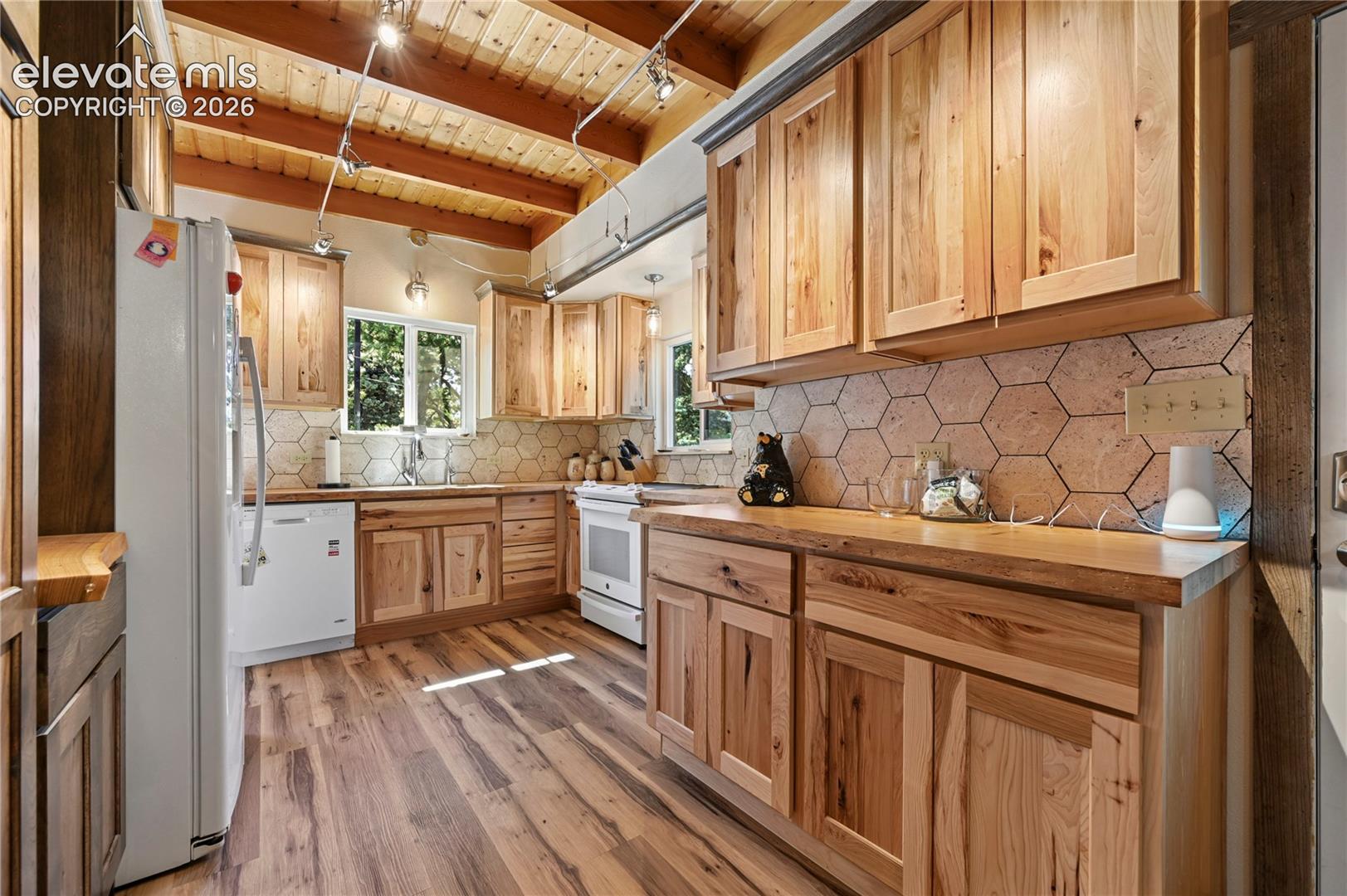 Kitchen featuring wood-finish flooring, natural wood cabinetry, wood countertops, and a hexagonal tile backsplash