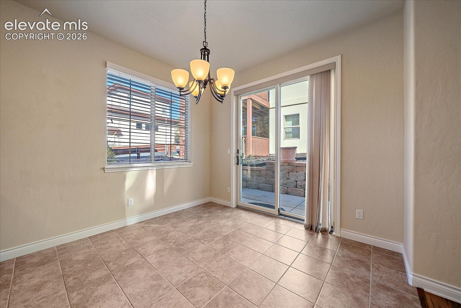 Ceramic tile flooring, five-light traditional chandelier, sliding glass door, and neutral-toned wall finish