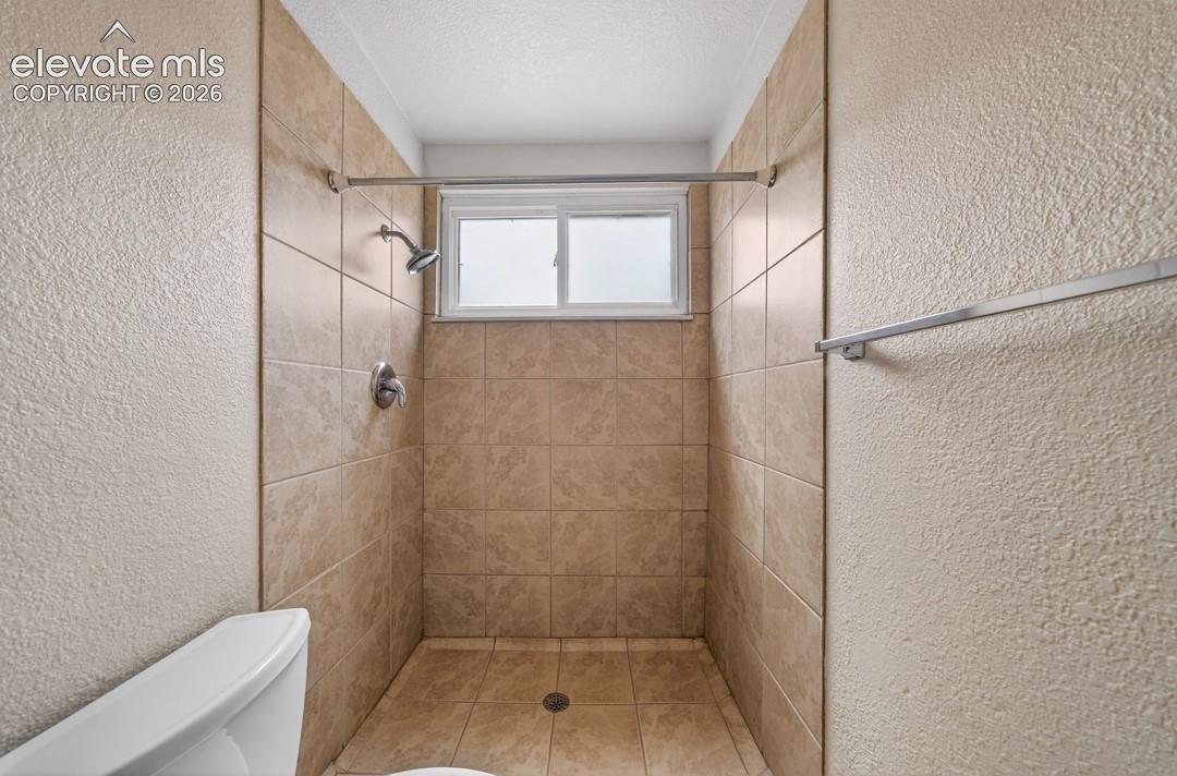 Tiled shower enclosure featuring a window and an integrated shower head with controls