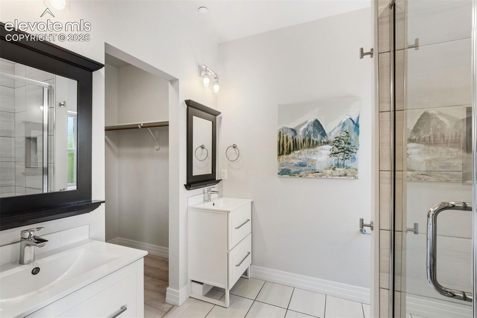 Primary ensuite bathroom with dual vanities, walk-in shower, and walk-in closet