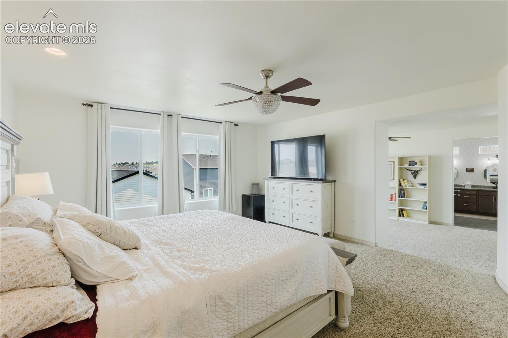 Bright interior space featuring a ceiling fan with integrated lighting, recessed lighting, and soft carpet flooring