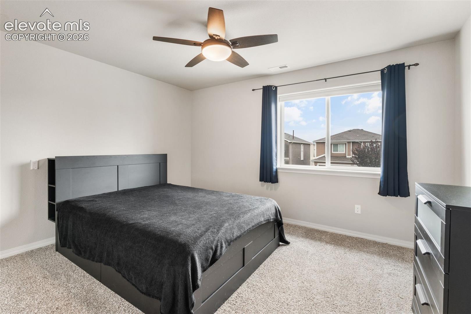 Wall-to-wall carpeting, window with a white frame, and a ceiling fan with integrated lighting