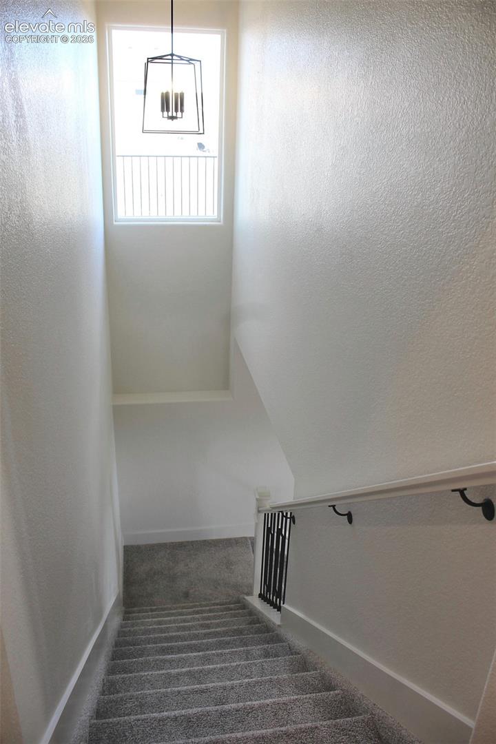 High ceilings, carpeted stairs, and a rectangular window with a black iron cage chandelier