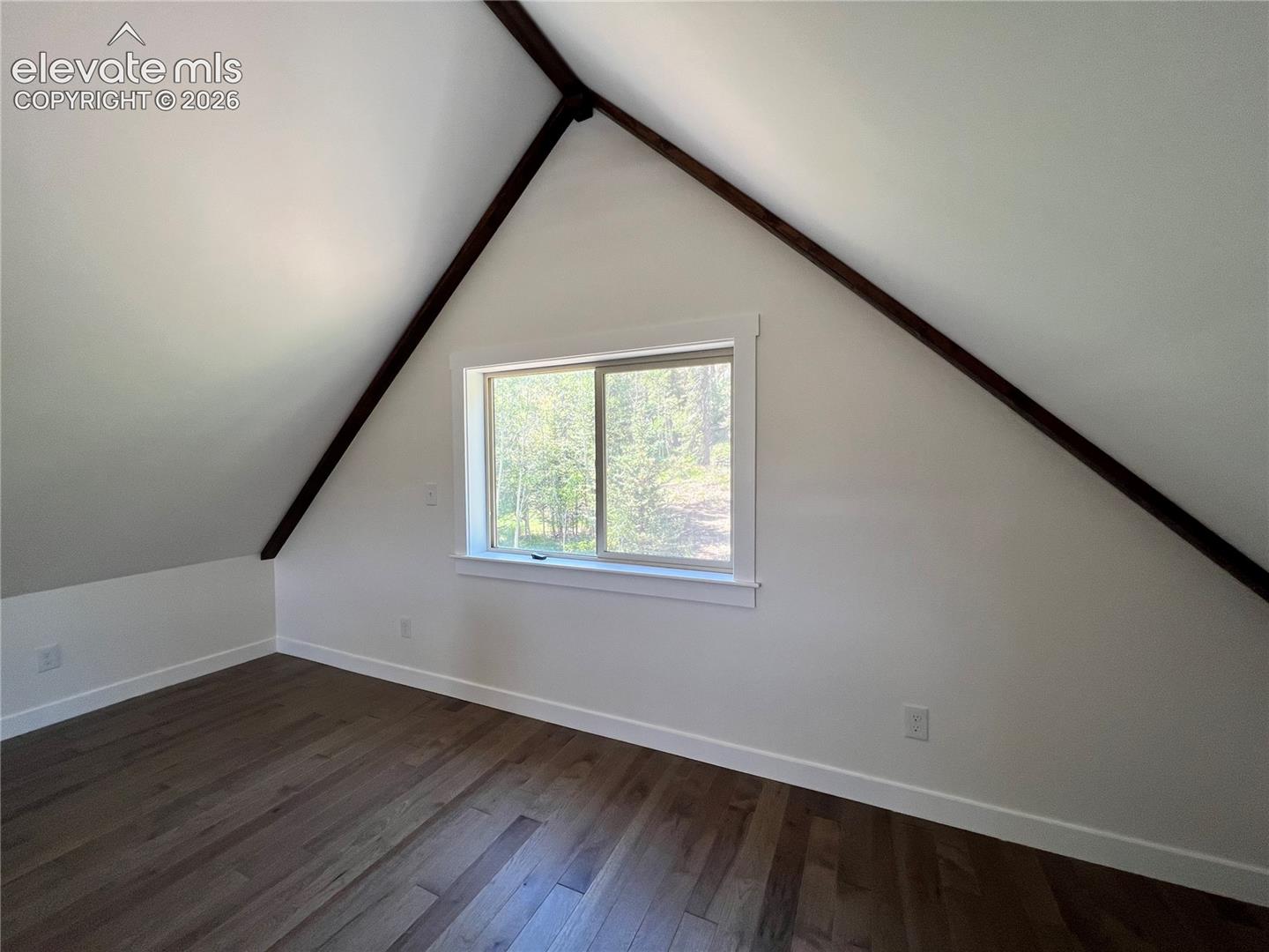 Wood-finish flooring, white walls, and a window with white trim