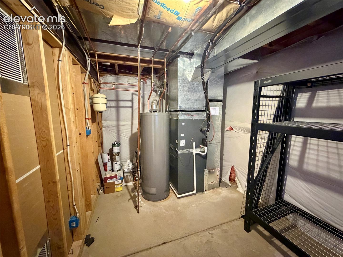 Dedicated utility area featuring a water heater, furnace system, copper piping, and exposed wooden framing