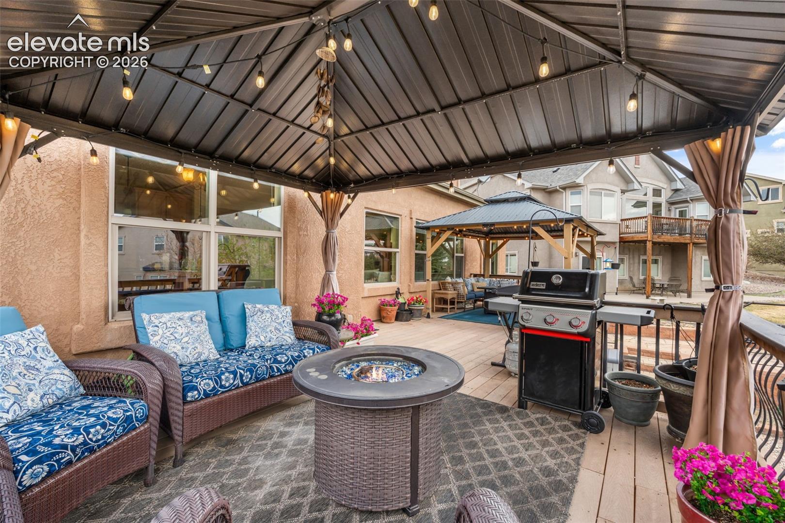 Covered patio featuring string lighting, a gas fire pit, and a built-in outdoor grill