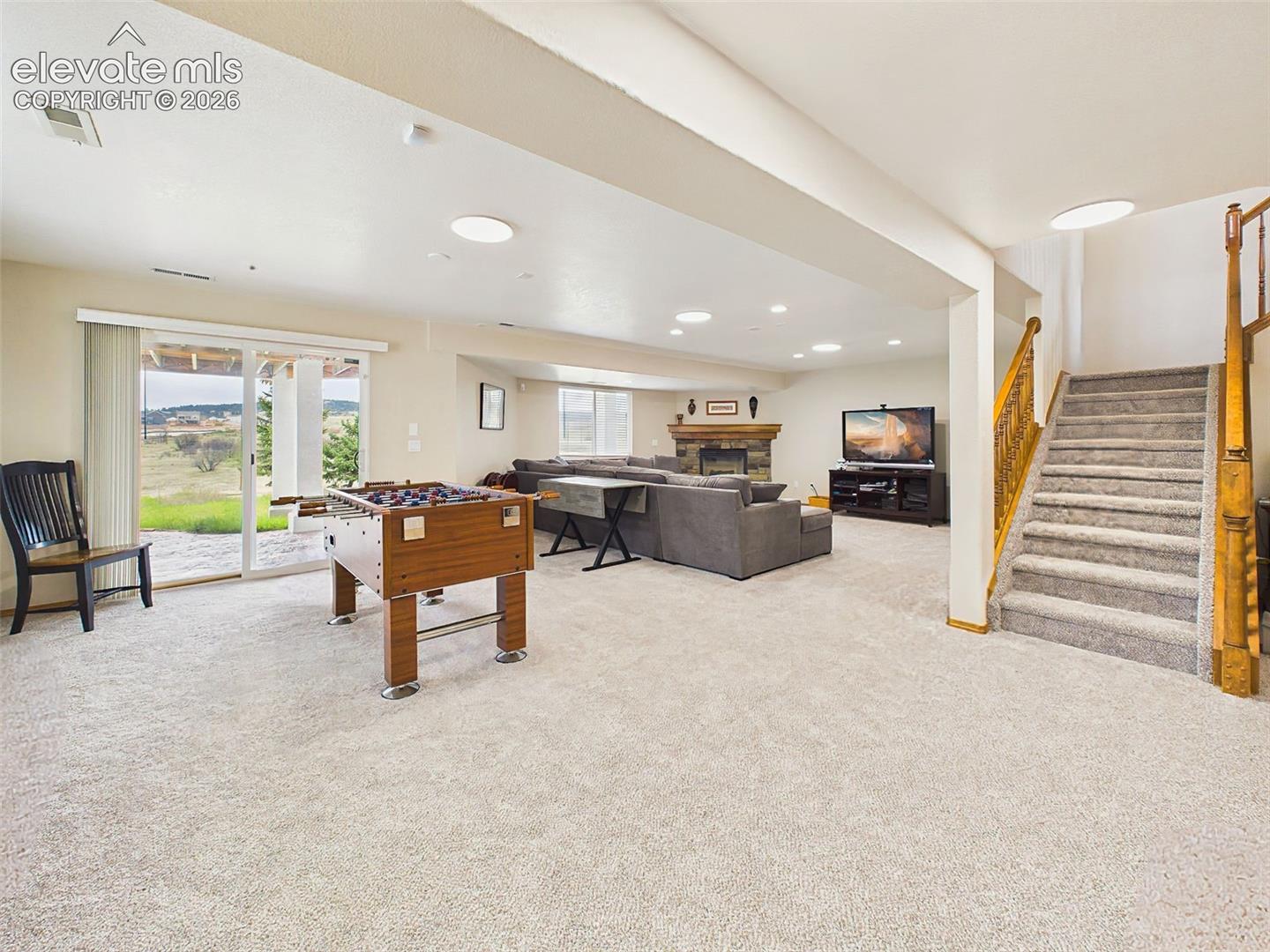 Expansive lower-level living area with plush carpeting, fireplace, and walkout access to the backyard patio—perfect for entertaining or relaxing.