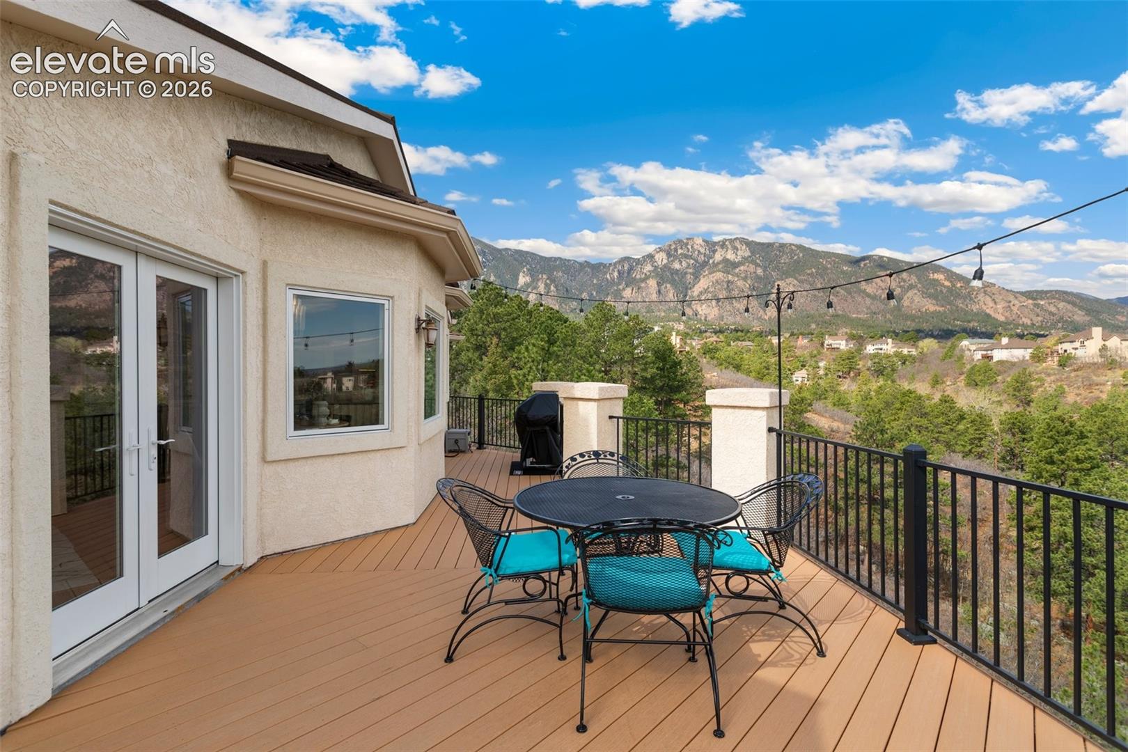 Expansive outdoor deck featuring composite decking, black metal railing, and stucco exterior