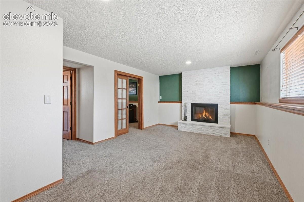 Recessed lighting, wood-trim baseboards, and a fireplace with a stacked stone facade