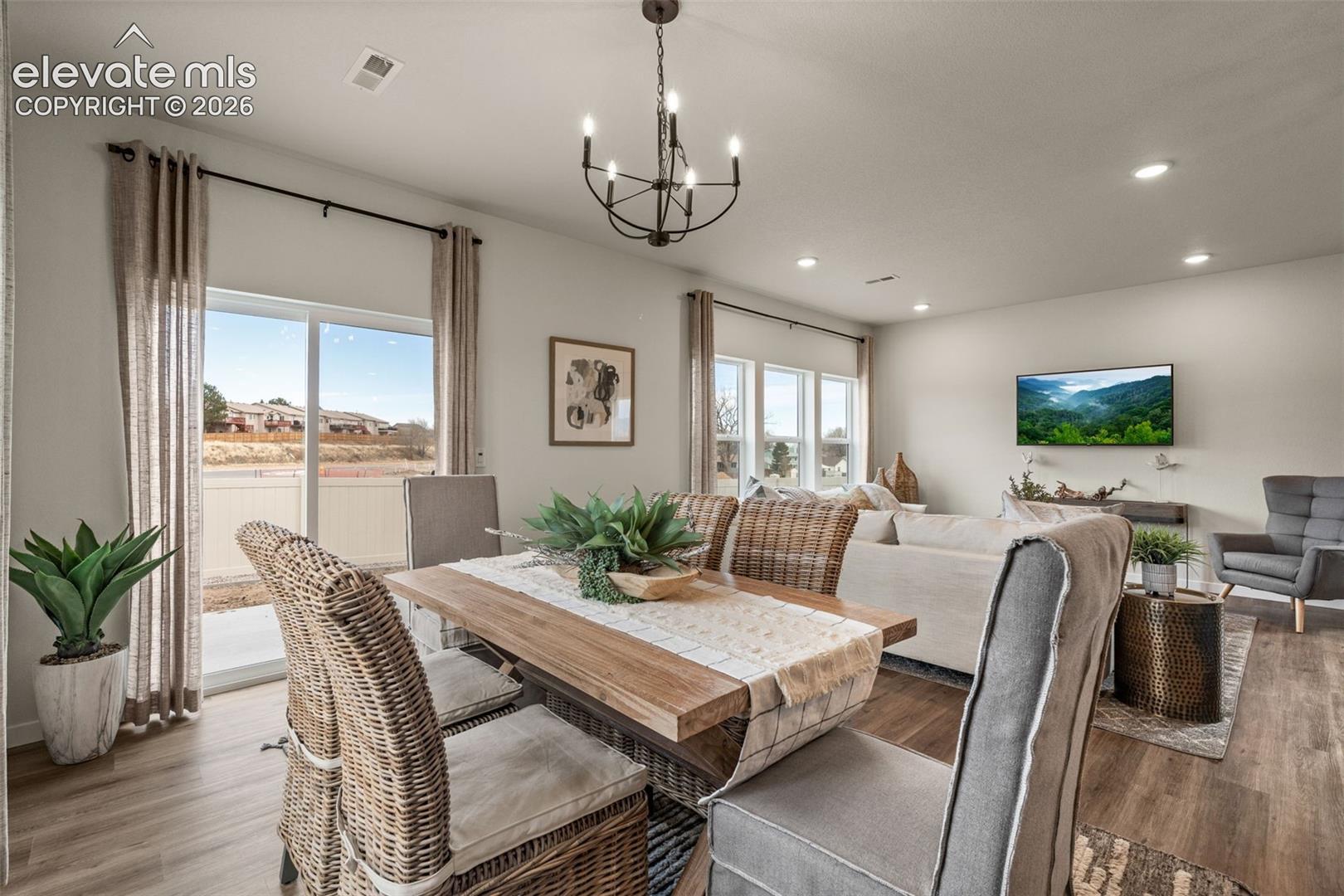 Open-concept living area with wood-finish flooring, recessed lighting, and a modern chandelier