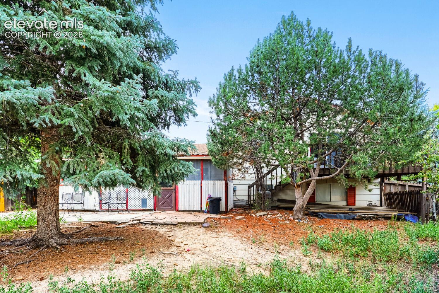 Exterior featuring mature trees, a ground-level patio, and an upper-level deck with exterior stairs