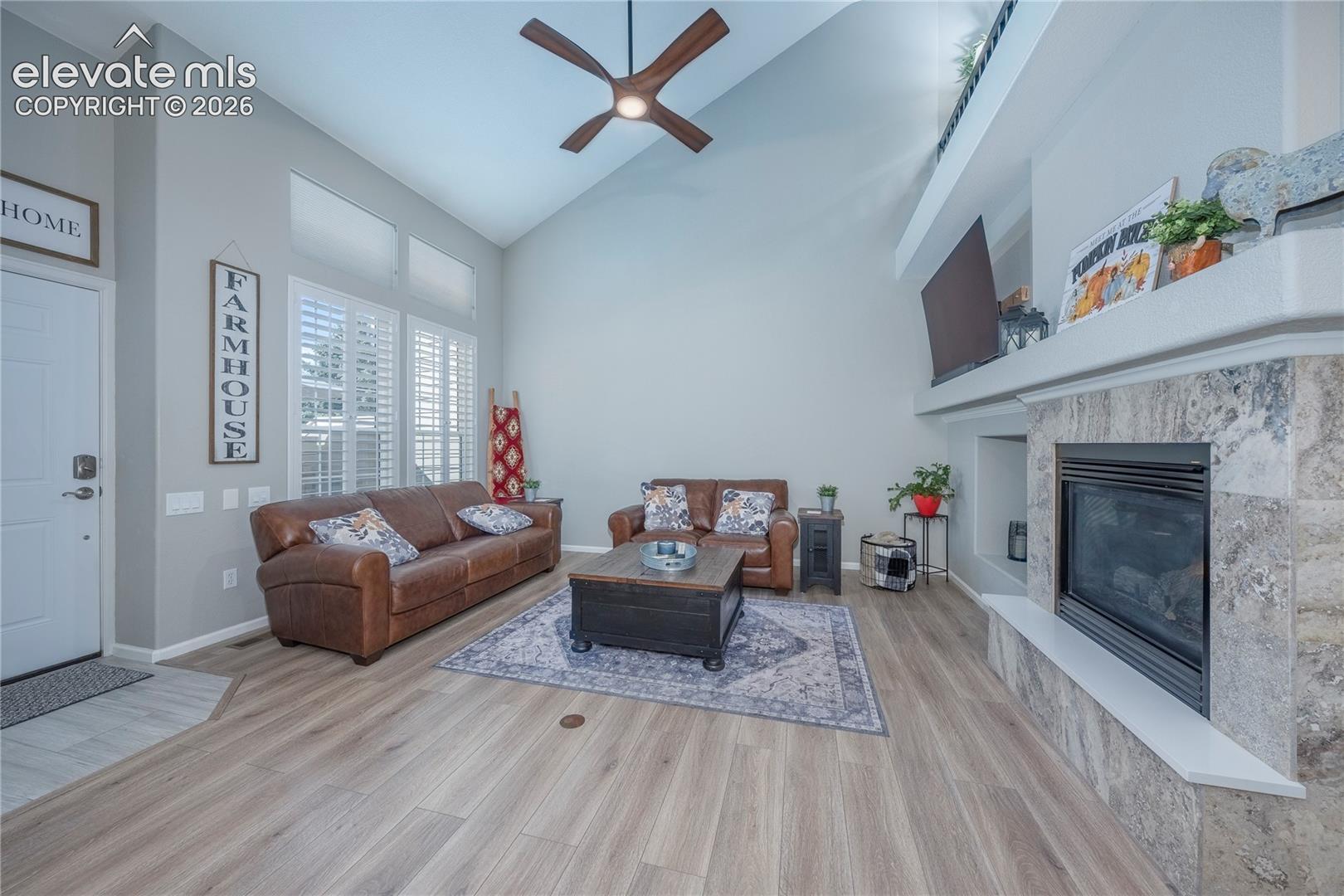 Vaulted ceilings, wood-finish flooring, stone-surround fireplace with hearth, and plantation shutters