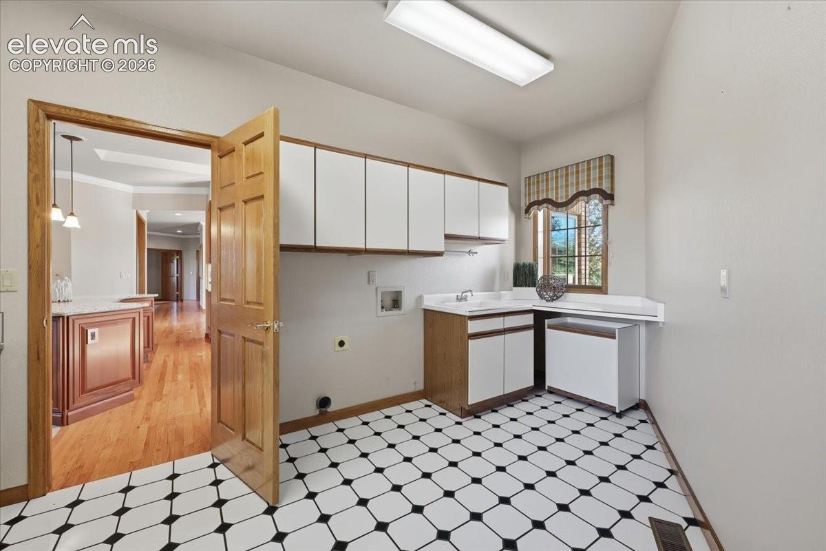 Laundry space offers a sink, window, and ample storage along with electric hookups. 