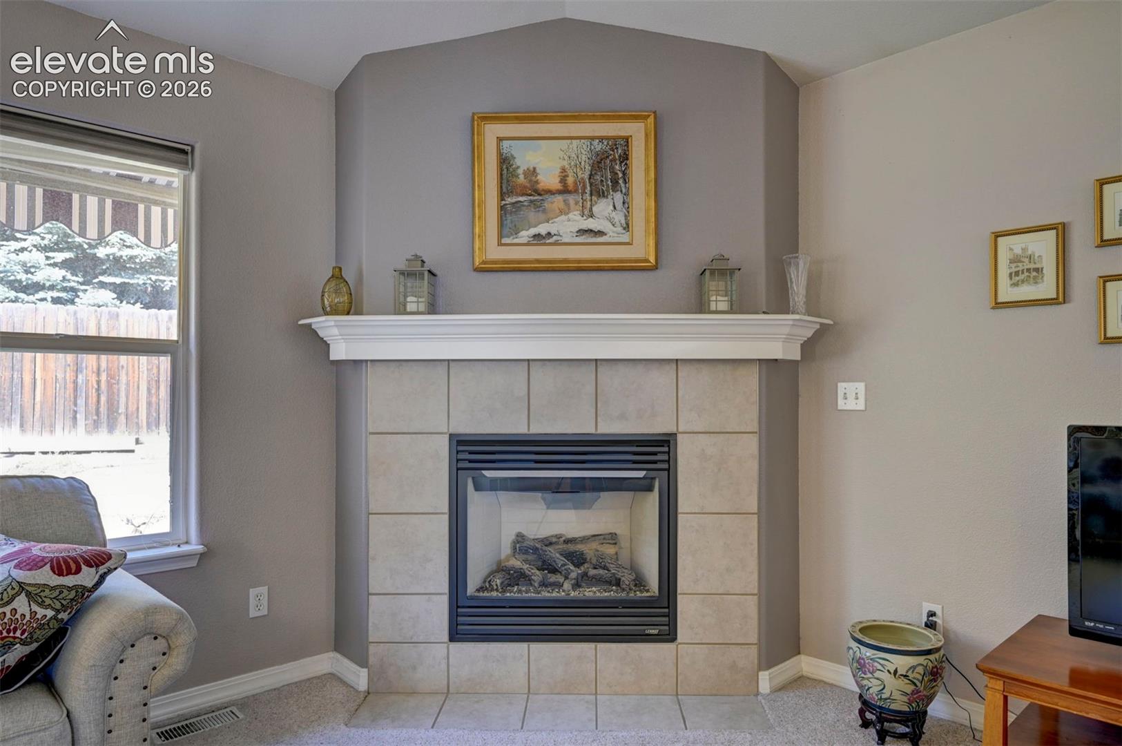 Gas fireplace with tile surround and wood mantle in living area.