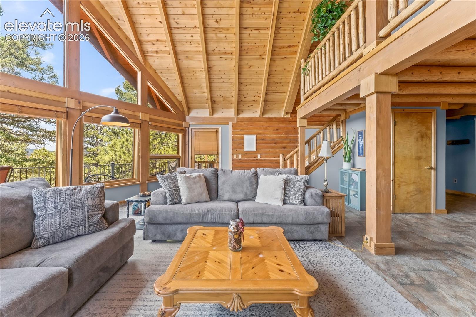 Vaulted wood-paneled ceilings, extensive window array, wood-finish flooring, and a natural wood staircase with log railings