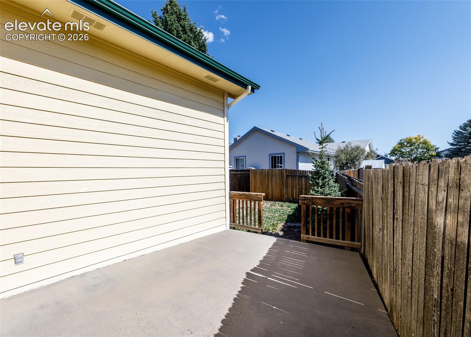 Concrete patio with wood fencing, wood siding, and gutters