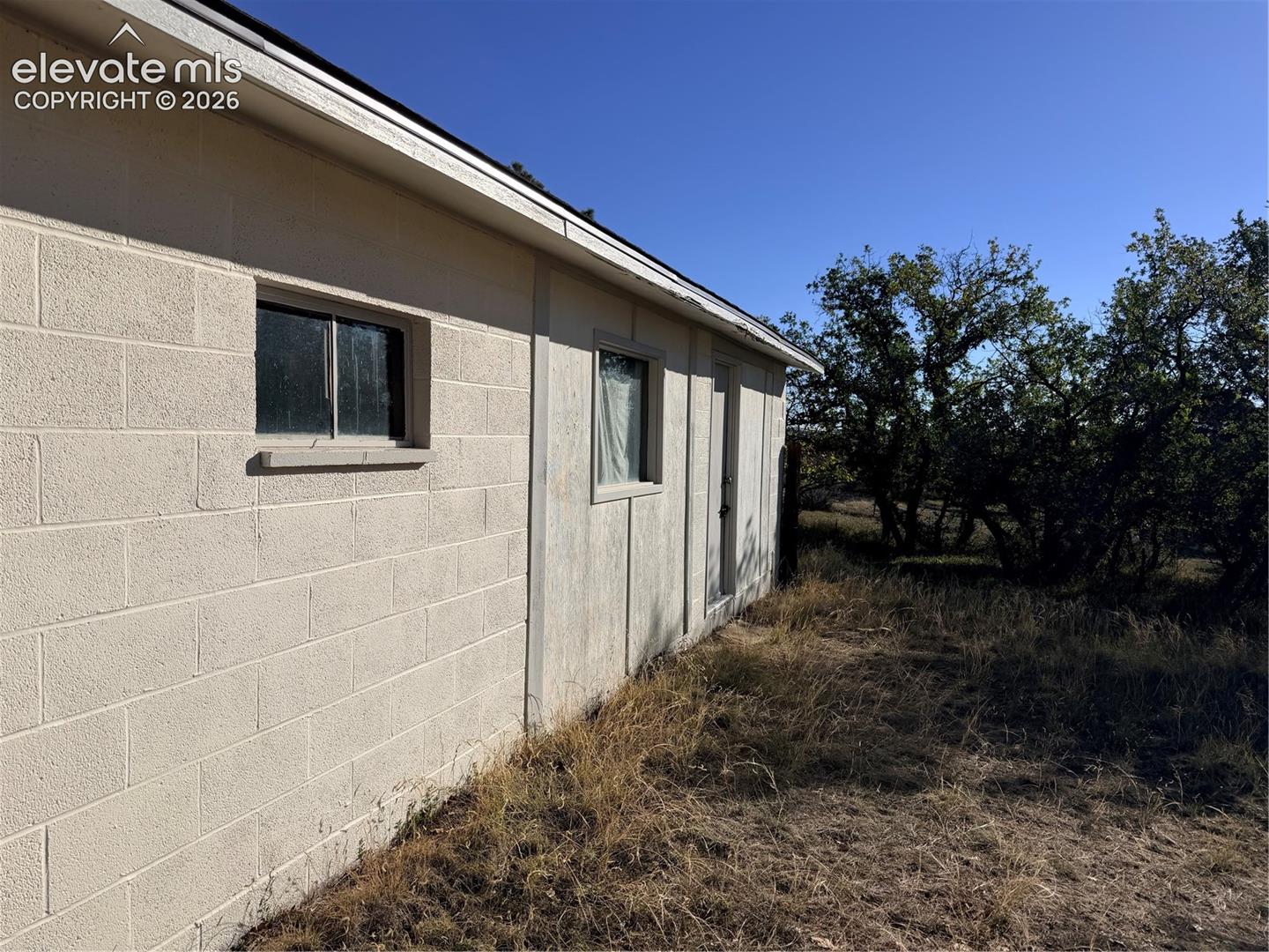 Concrete block exterior wall with single-pane windows and a side-entry door