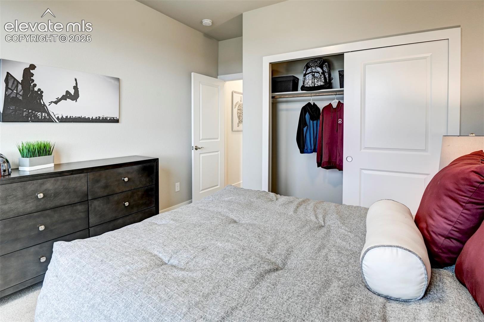 Recessed lighting, wood-finish dresser with metal hardware, and a built-in closet with sliding panel doors