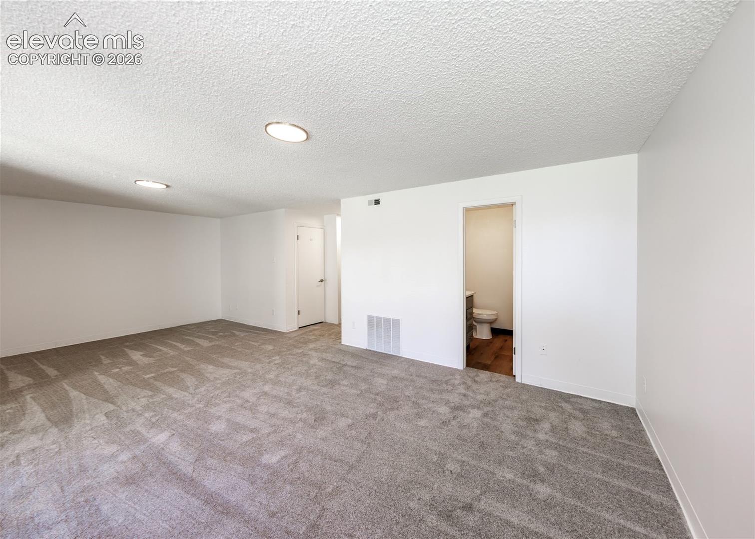 Interior space featuring neutral-toned carpeting, recessed ceiling lighting, and solid-core interior doors