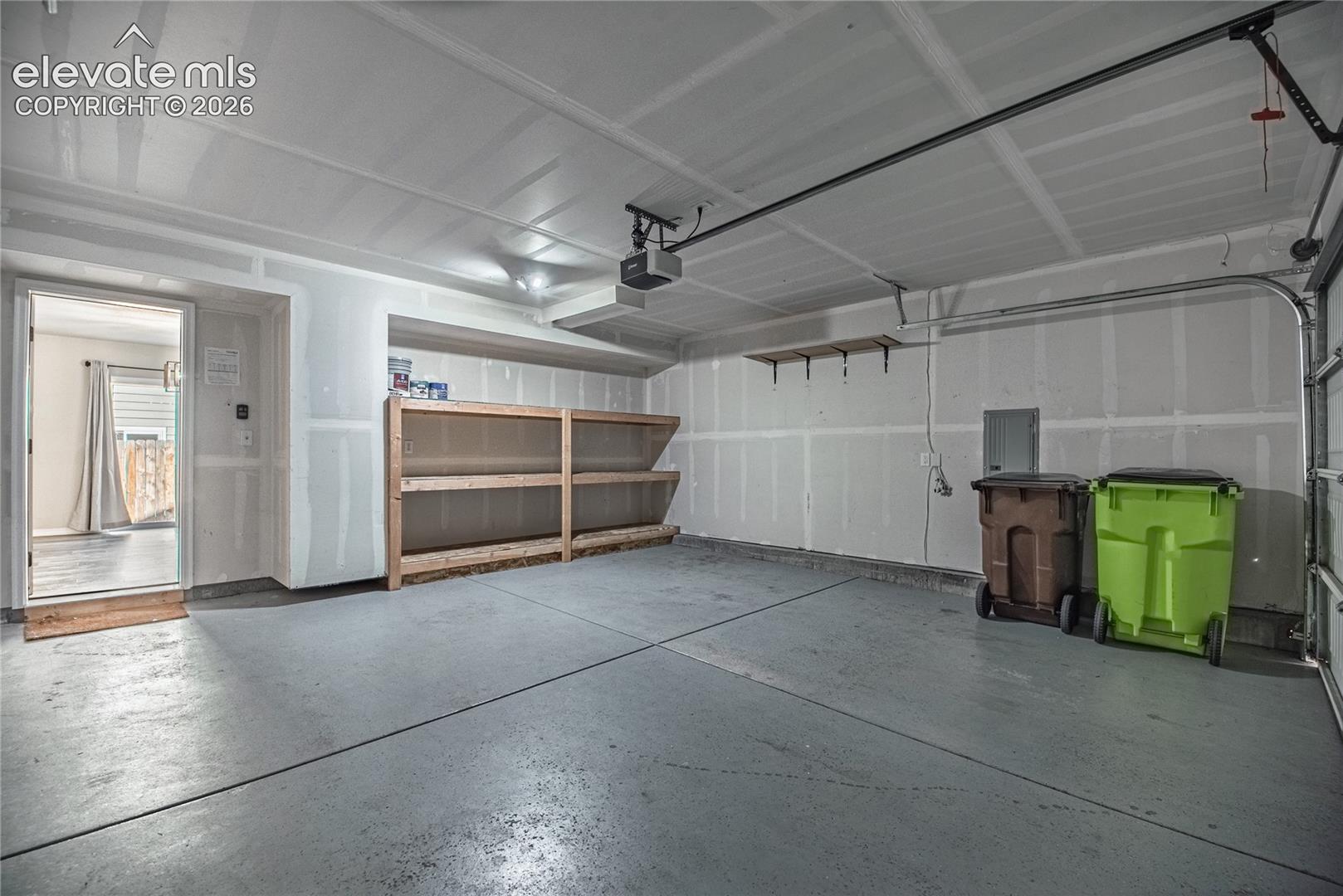 Spacious garage with an overhead door, built-in shelving, and a concrete floor