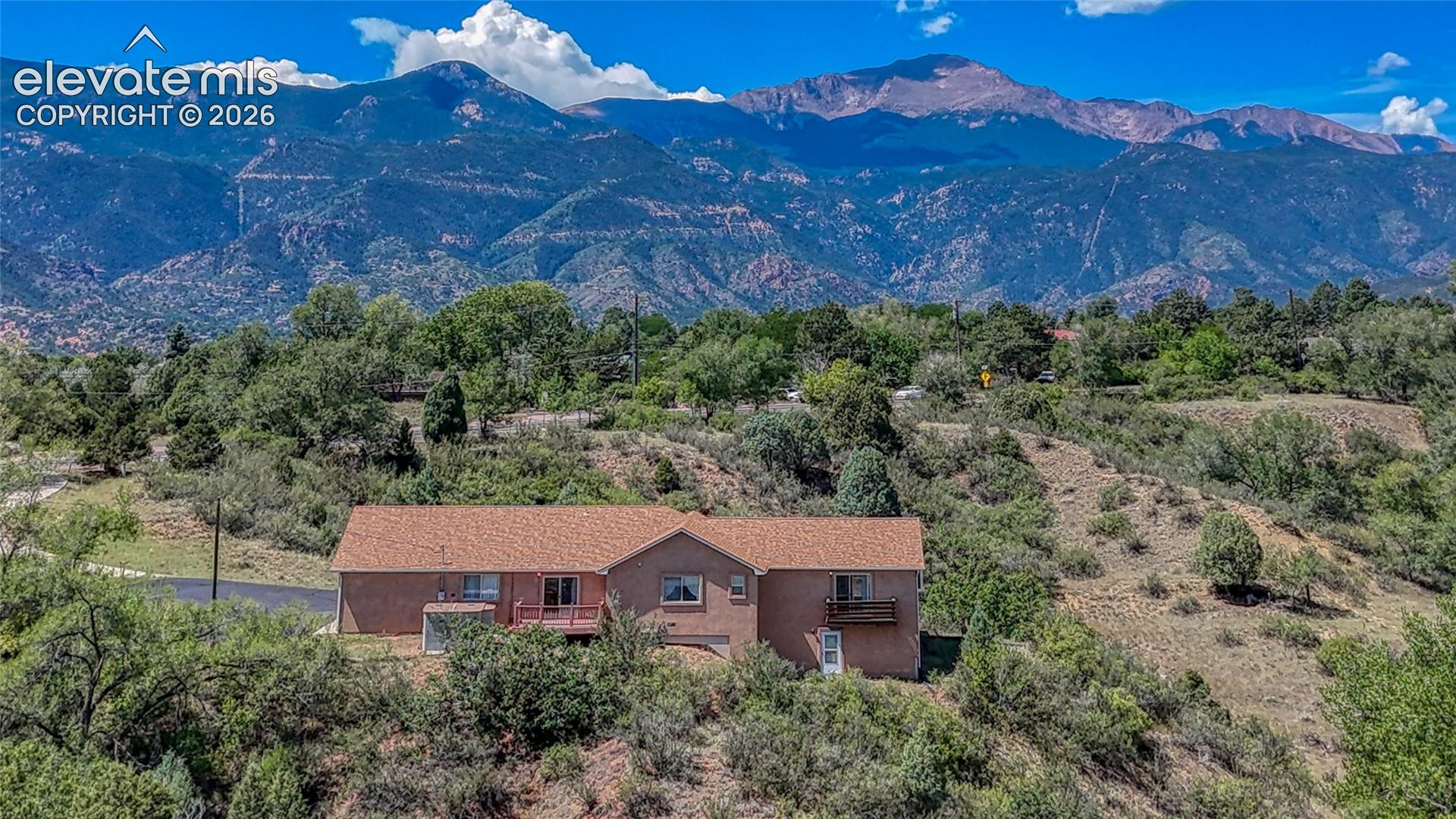 RARE OPPORTUNITY w/ incredible PIKES PEAK, mountain & CITY VIEWS in an exceptional Colorado Springs setting! This custom home is situated on a rare large lot nestled against expansive open space, creating a remarkable sense of privacy & the feeling of having 40 acres right outside your door.  Surrounded by natural vegetation & sweeping Front Range scenery, this is a setting that is truly hard to duplicate! Stucco exterior, stone accents & an expansive Trex front deck set the stage. Step inside to a spectacular great room wrapped in warm wood walls & soaring wood ceilings w/ exposed beams, abundant natural light & an impressive stone fireplace anchoring the space. Multiple doors open directly to the deck, seamlessly extending the living area outdoors to enjoy the peaceful surroundings. Spacious kitchen features abundant wood cabinetry, generous counter space, center island w/ cooktop & prep sink, built-in oven, desk/workstation & an adjoining dining area surrounded by windows. The main bedroom is generously sized w/ deck access plus a NEW bay window, while the spacious ensuite bath offers dual sinks, soaking tub & separate glass-enclosed shower. 3 beds/3.5 baths provide excellent flexibility throughout the home. Multiple decks take advantage of the elevated setting, natural landscape & outstanding views. The HEATED oversized 3-Car w/ workshop is a huge bonus w/ exceptional room for vehicles, storage, toys or hobbies. Additional improvements include Trex decking, exterior stucco, added AIR CONDITIONING & a whole-house water purification system. The nearly 1-acre lot backs/nestles against expansive open space, giving the property an incredible feeling of separation while still offering convenient Colorado Springs living. Enjoy Pikes Peak, mountain & city views from this one-of-a-kind setting. Custom home + huge lot + open space + 3-car garage + views = an incredible combination. MUST SEE!
