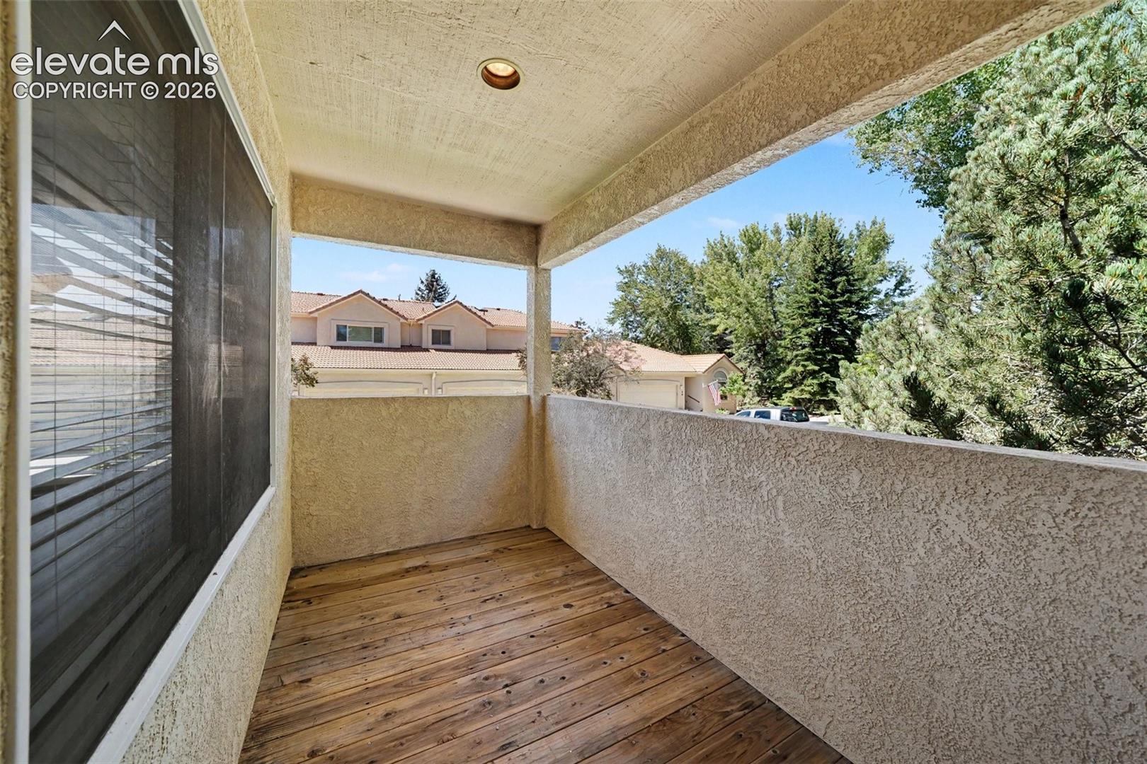 Balcony featuring a wood-finish floor, textured exterior walls, and a recessed ceiling light