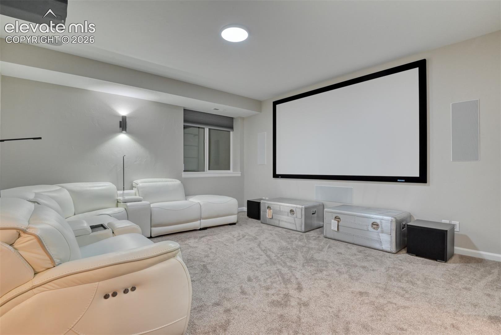 Built-in projection screen, recessed ceiling lighting, wall-mounted sconce lighting, and integrated wall speakers.