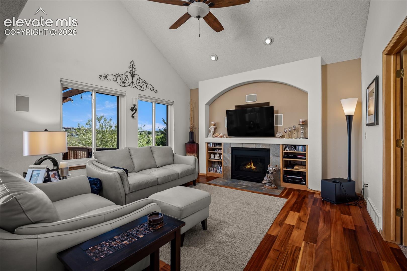 Vaulted ceiling family area featuring rich Brazilian Koa hardwood flooring, a built-in gas fireplace, an arched media alcove with surround sound built-in speakers.