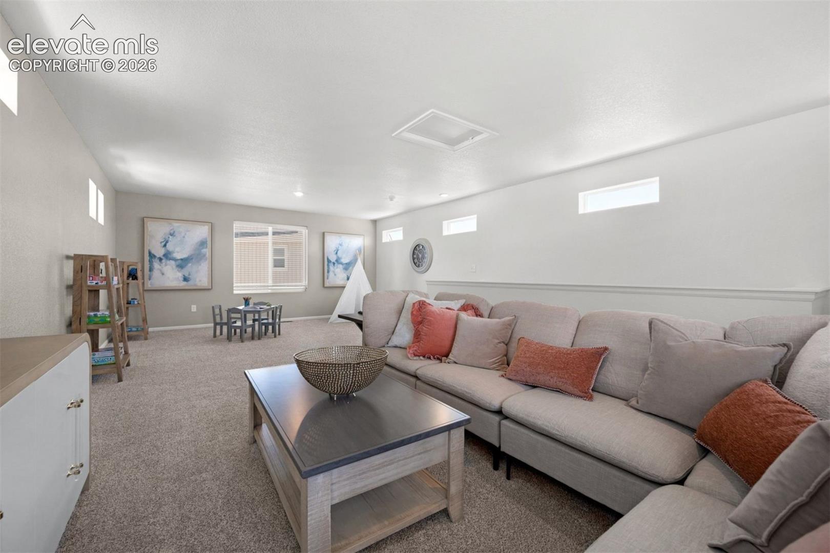 Spacious carpeted room featuring multiple windows, a ceiling light fixture, and built-in cabinetry with gold-tone hardware
*photos of a model home*