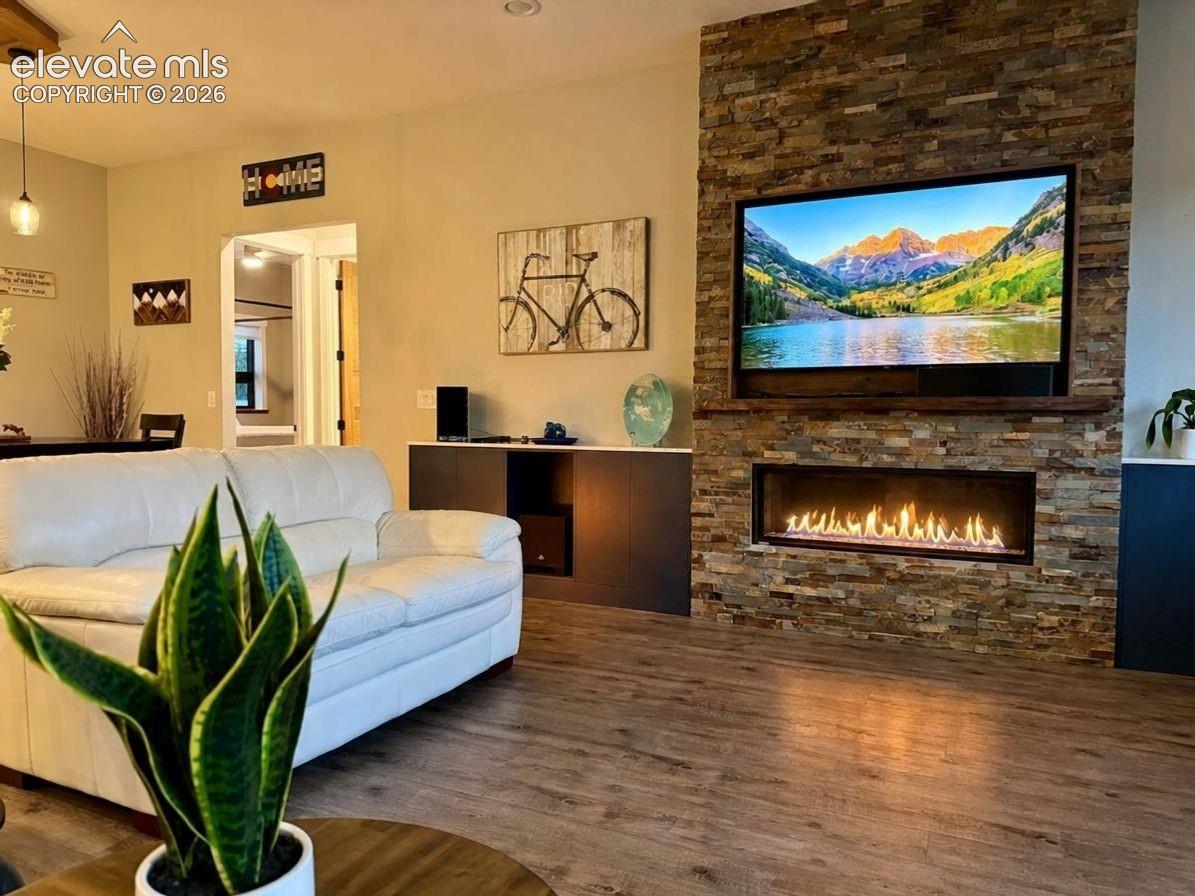 Stacked stone fireplace with a linear insert, wood-finish flooring, and recessed ceiling lighting