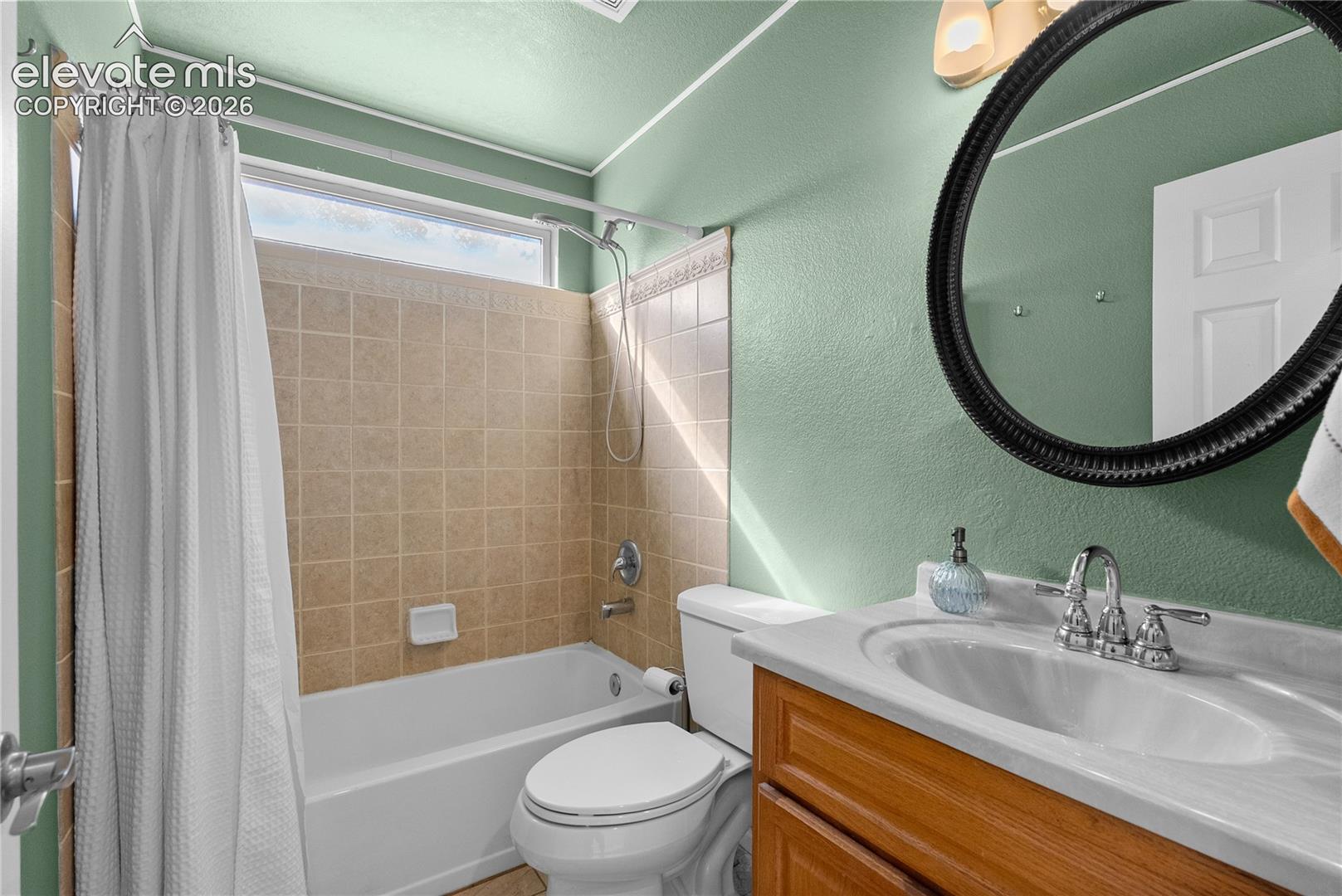 Bathroom with a built-in tub, tiled shower surround, and upper transom window