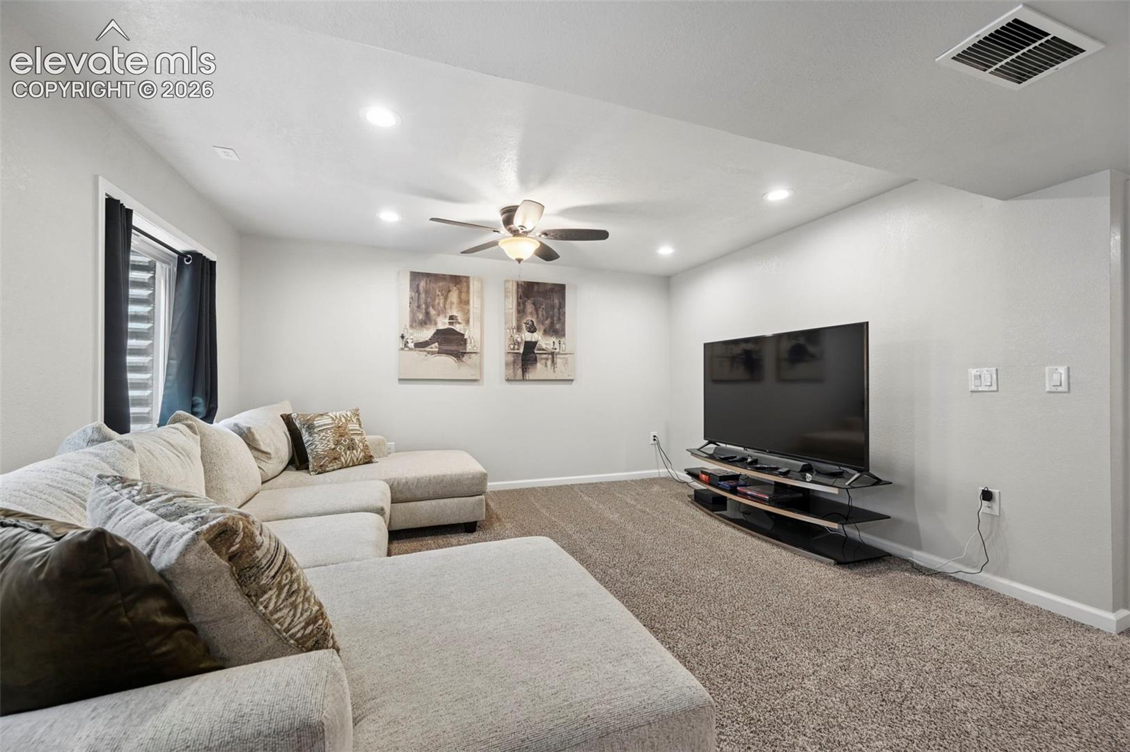 Recessed ceiling lighting, ceiling fan, carpeted flooring, and a window with a window well