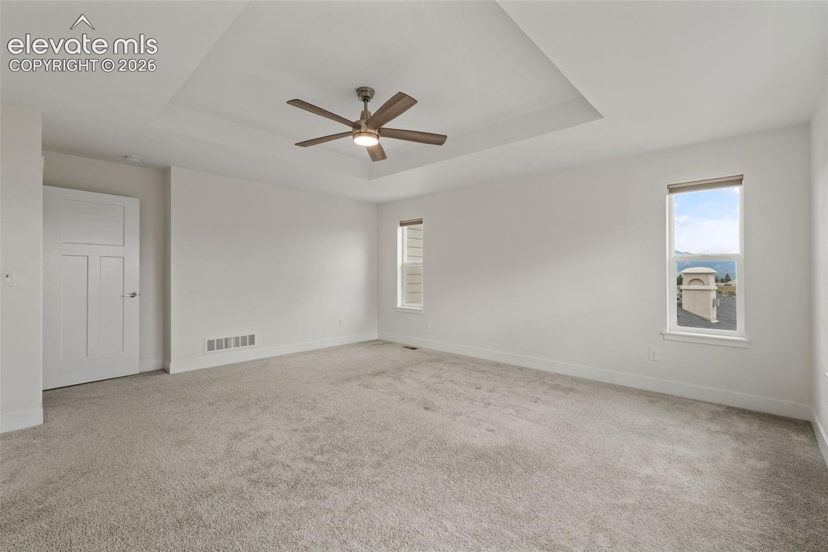 Recessed ceiling with an integrated ceiling fan, light gray carpeting, and mountain views
