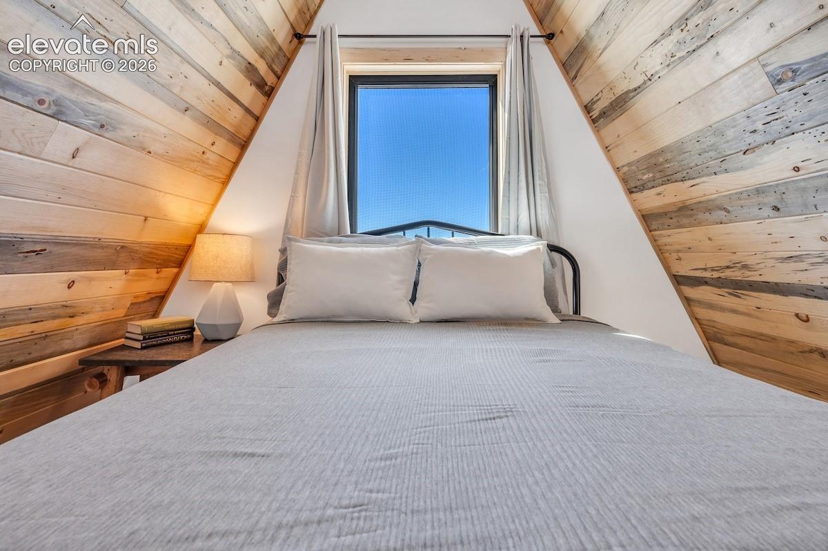 A-frame architectural structure featuring interior horizontal wood-plank wall paneling and a central fixed window