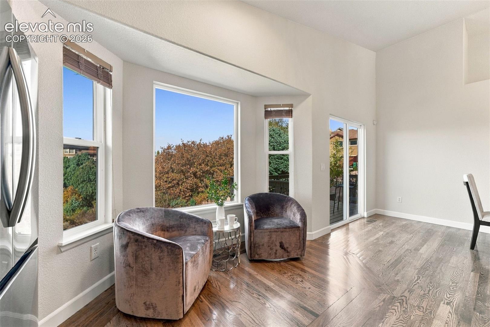Vaulted ceilings, expansive bay windows, wood-finish flooring, and sliding glass door with external deck access