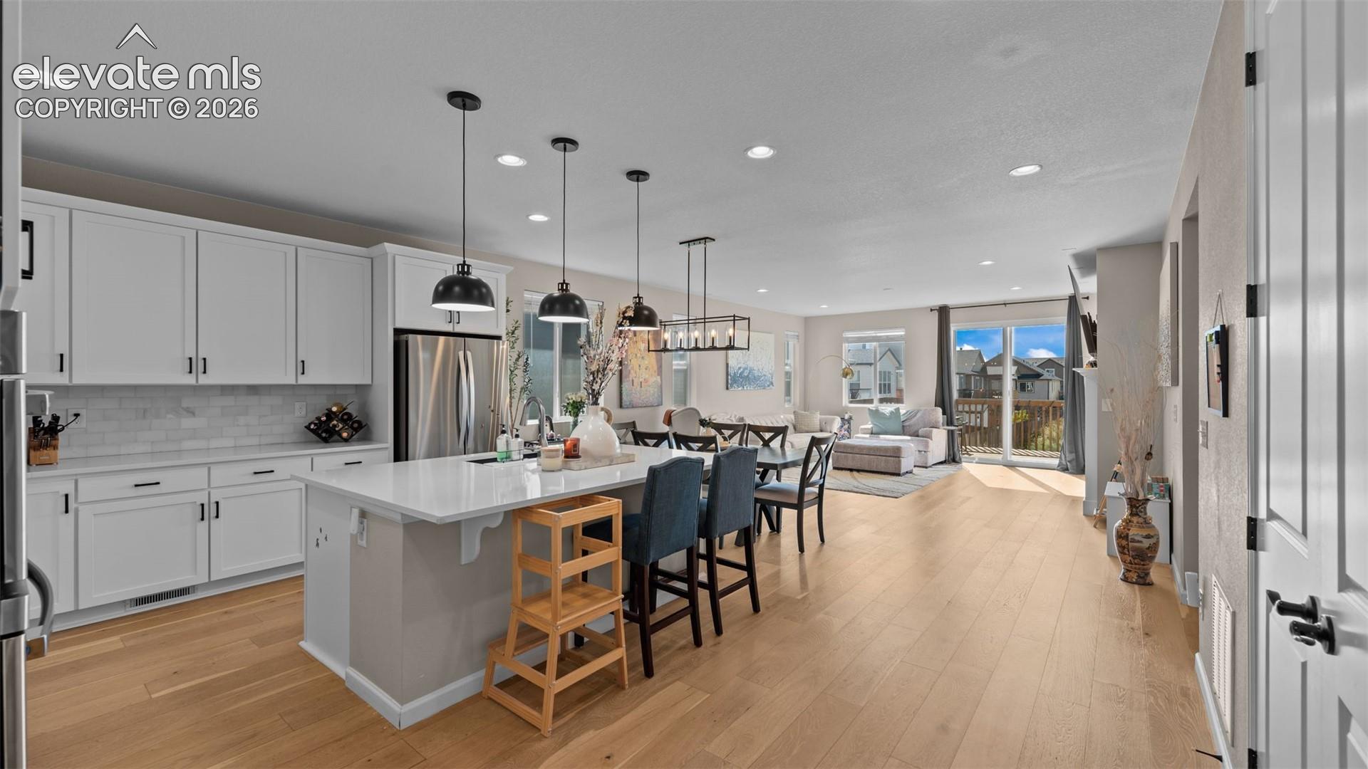 Kitchen featuring white cabinetry, subway tile backsplash, stainless steel appliances, and a central island with counter seating