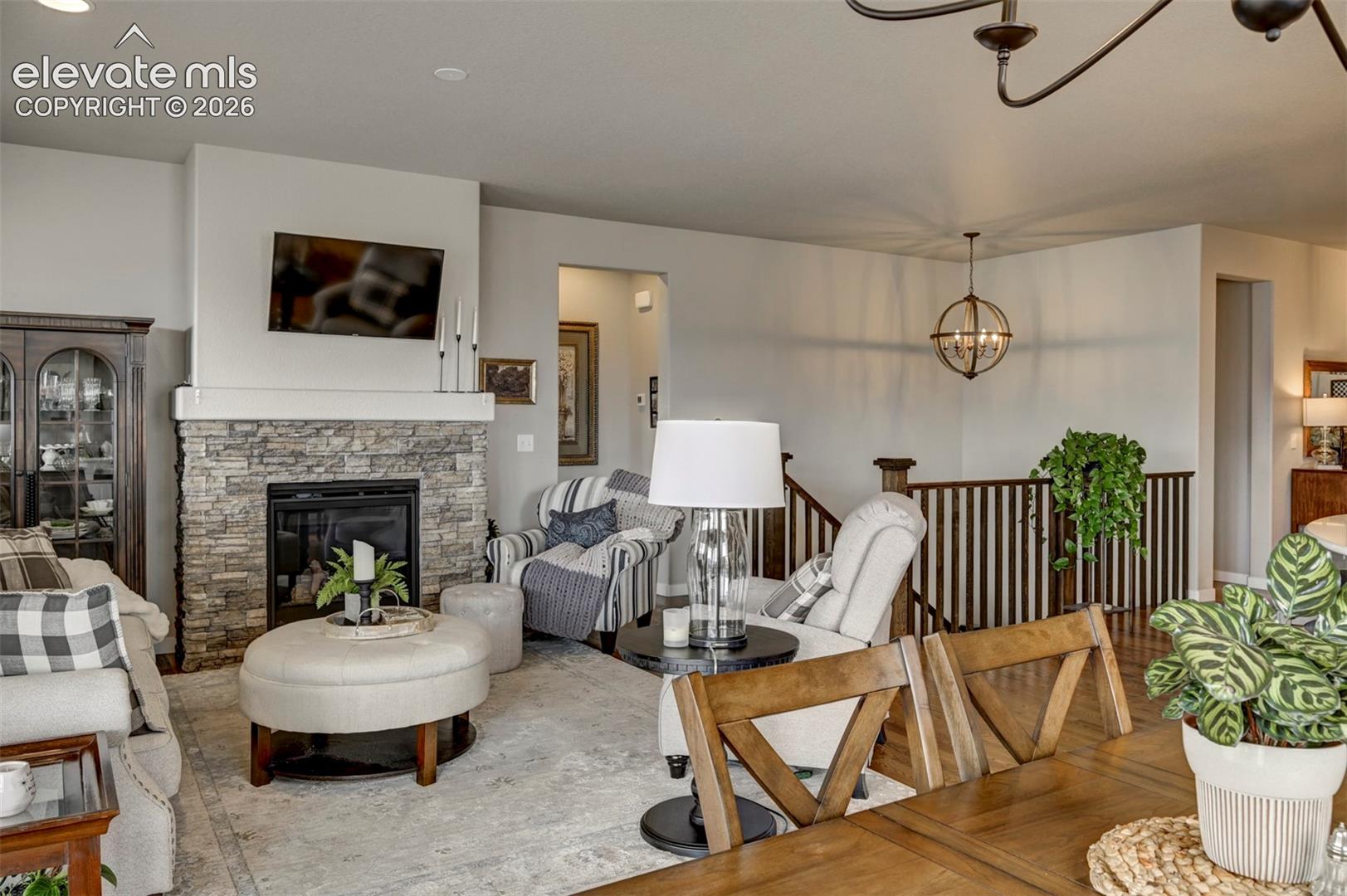 Stacked stone fireplace with a substantial hearth, built-in television mount, and hardwood stair railing with vertical balusters